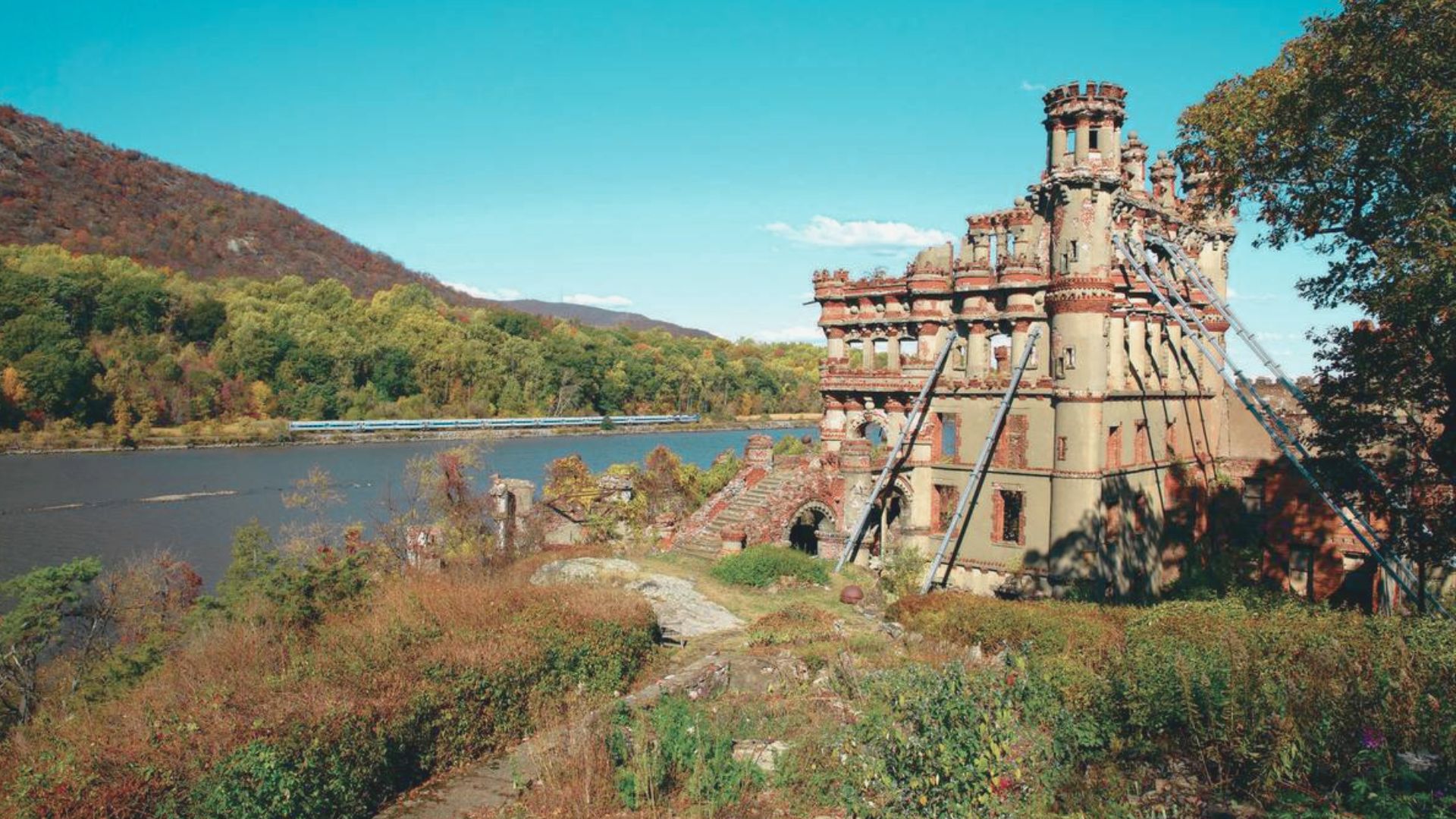 The ruins of a castle are perched at the river's edge, evoking a sense of mystery and history in the landscape.