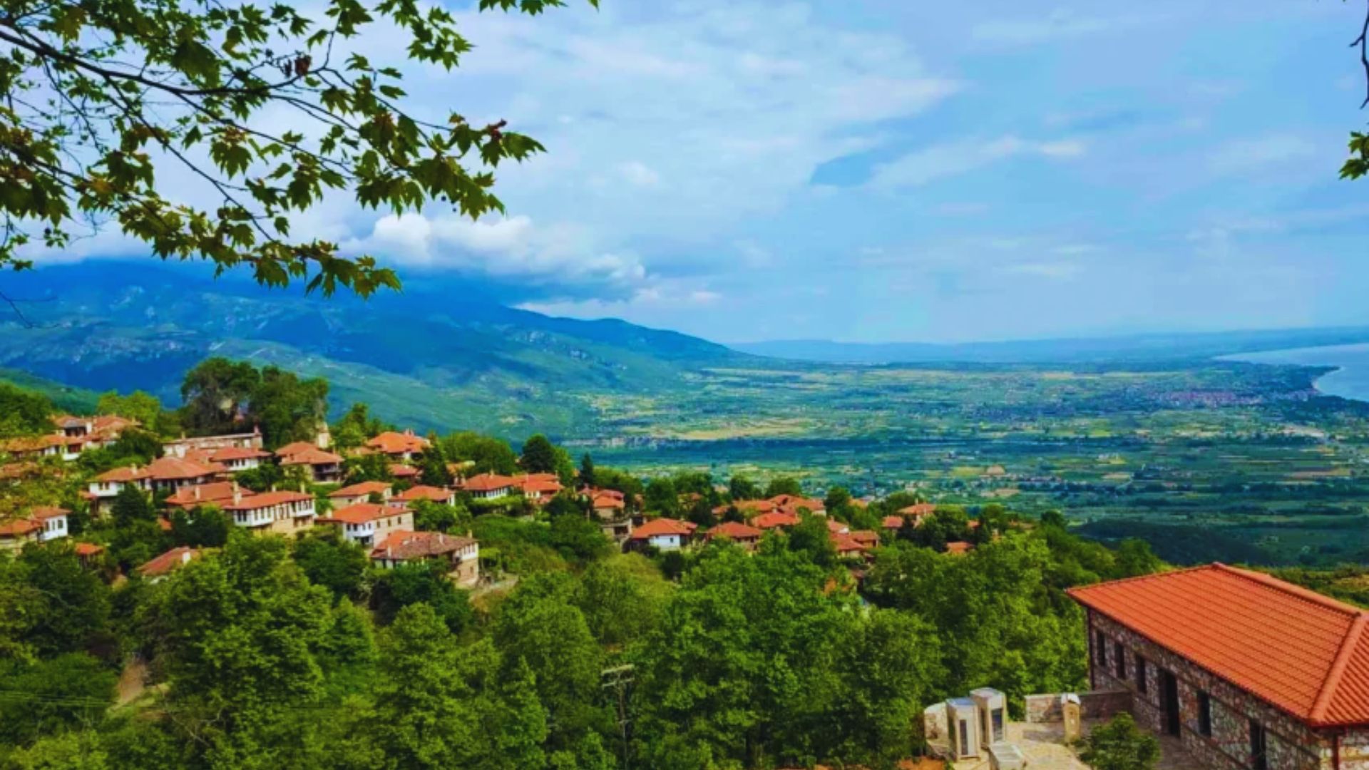 A panoramic view from a hilltop, showcasing a picturesque village nestled in the valley below.