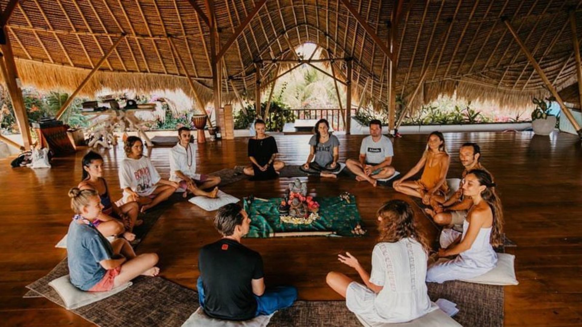A diverse group of people seated in a circle, engaged in discussion within a well-lit room.