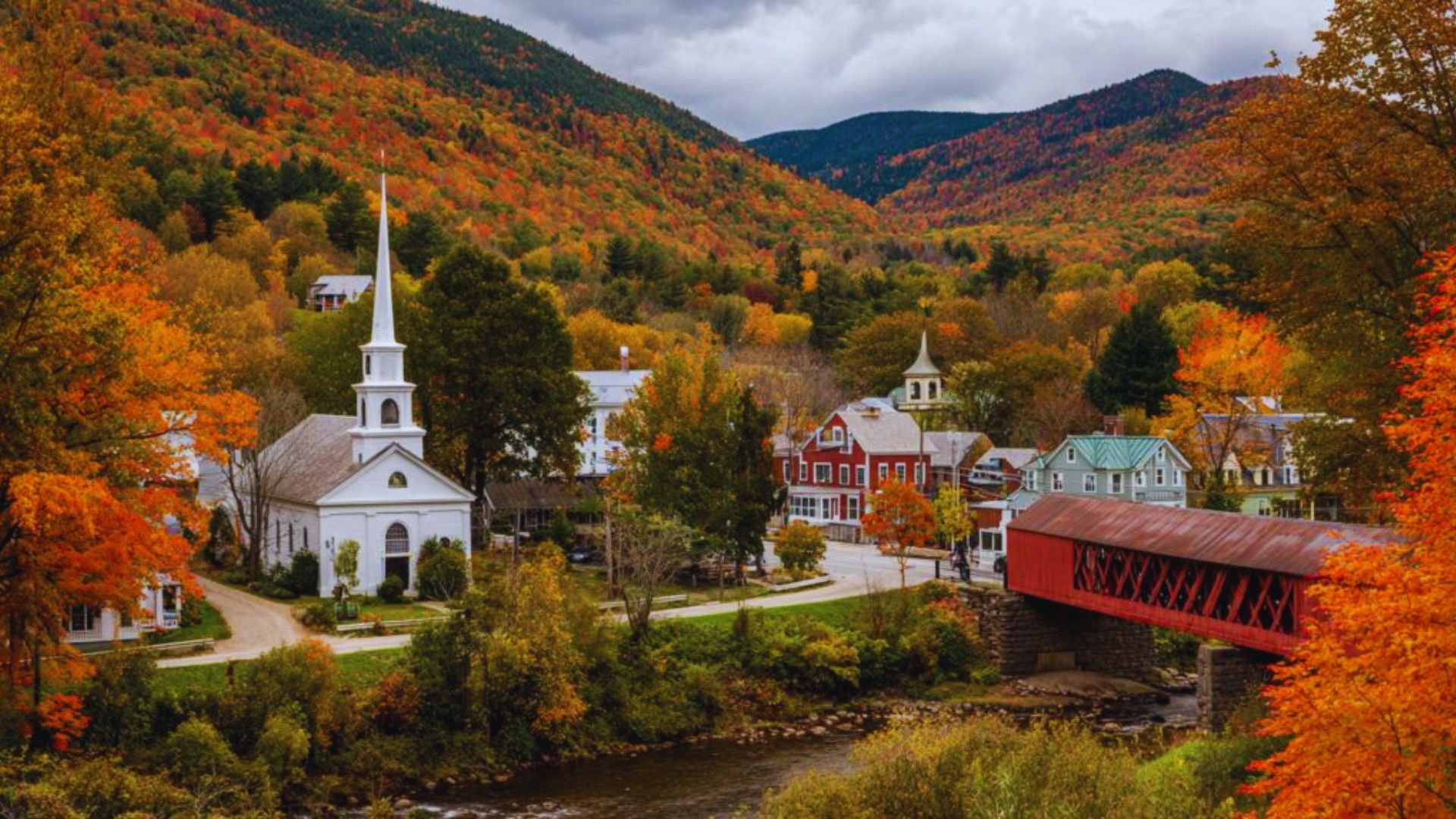 A picturesque covered bridge in Vermont surrounded by vibrant fall foliage.