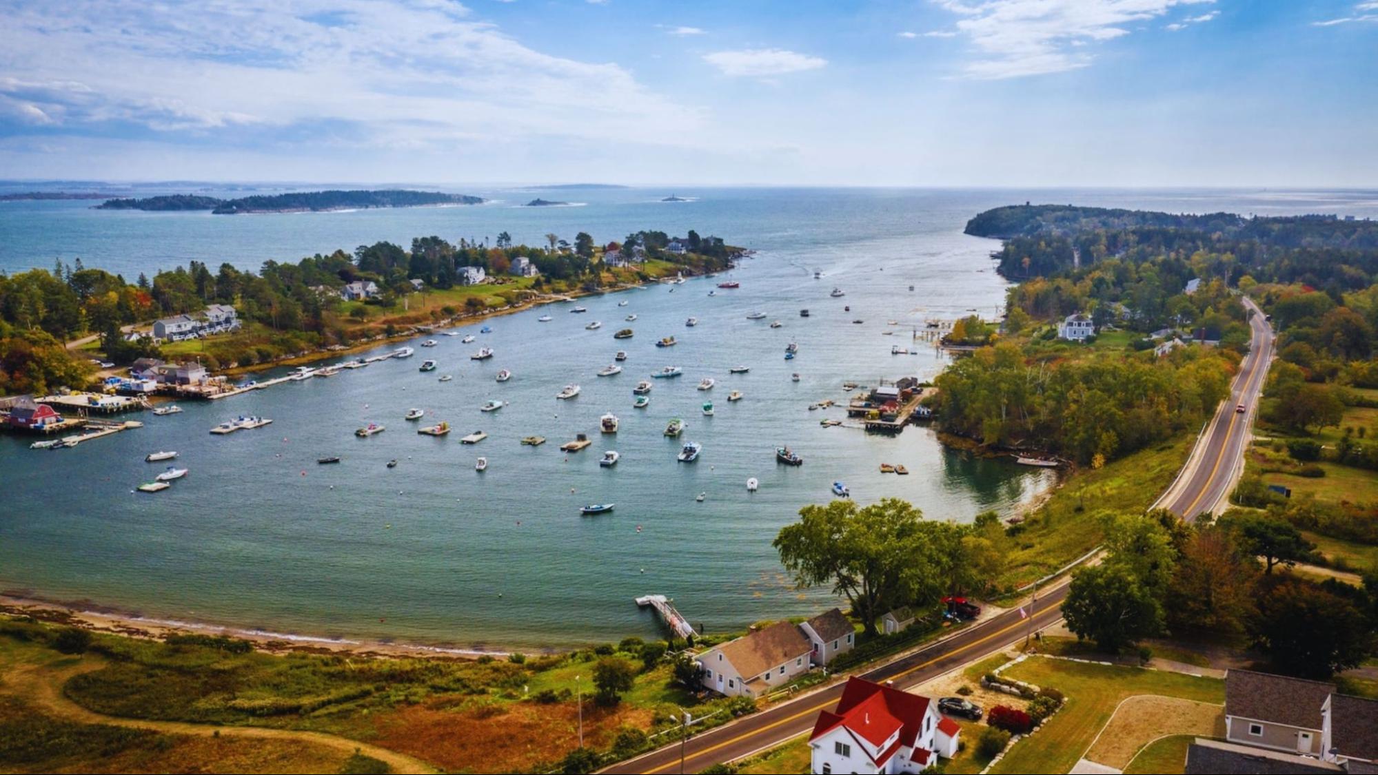 Aerial view of several boats floating on calm water, showcasing their varied colors and sizes against the blue backdrop.