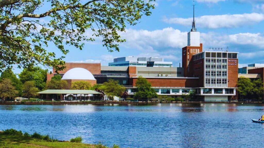 A boat floats on the water in front of a building, creating a serene waterfront scene.