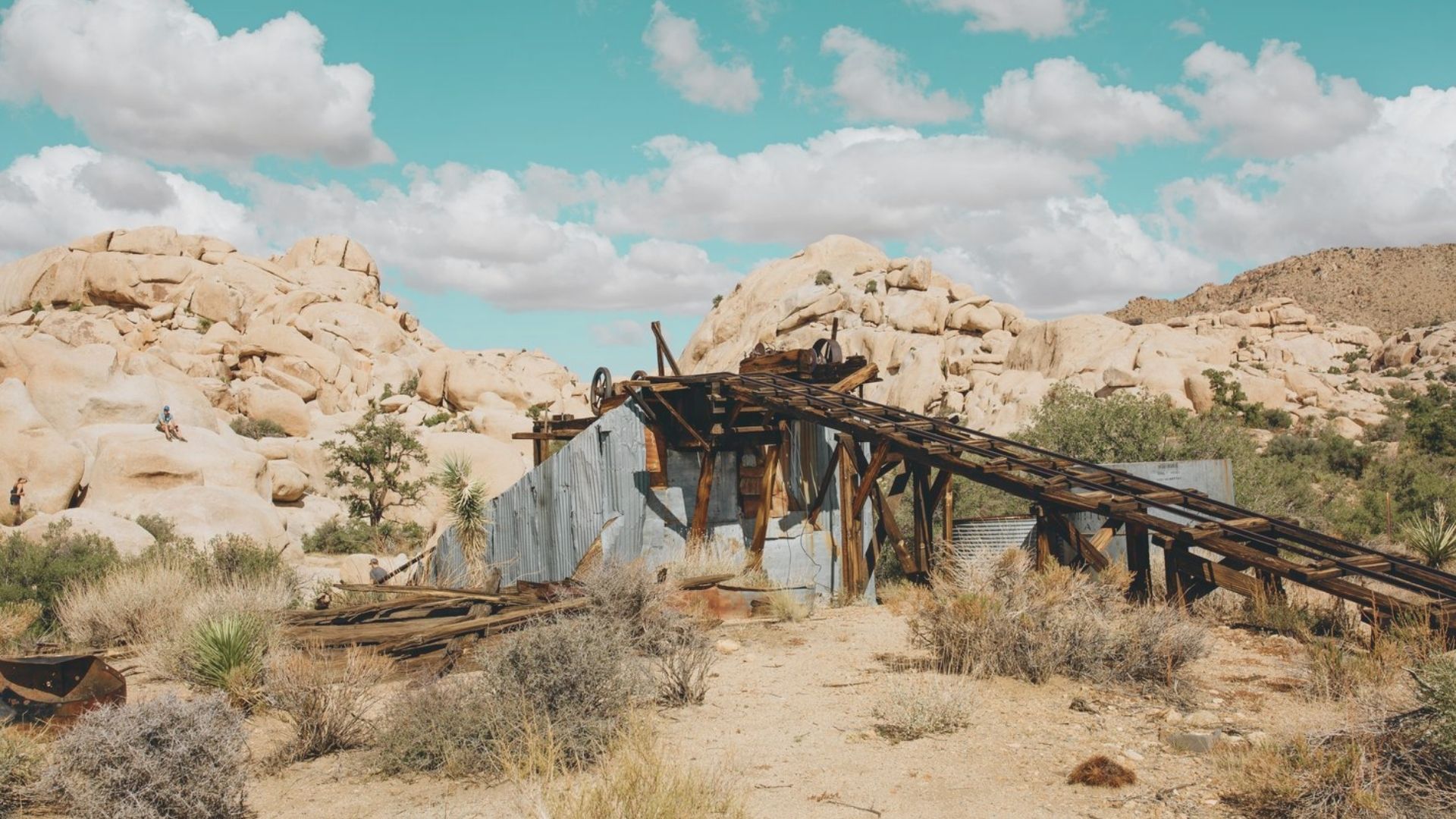 An old, abandoned mine surrounded by arid desert landscape under a clear blue sky.