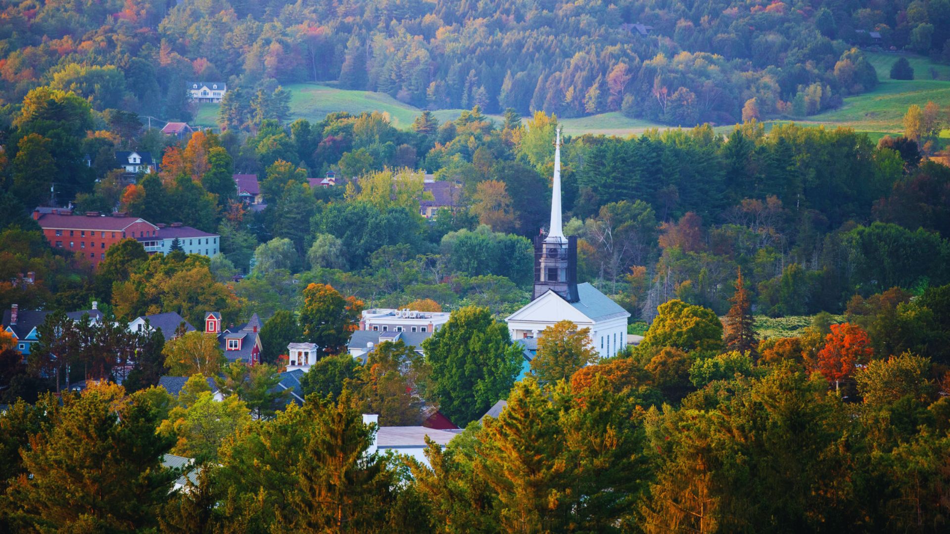 A scenic view of a quaint town featuring a prominent steeple rising in the background.