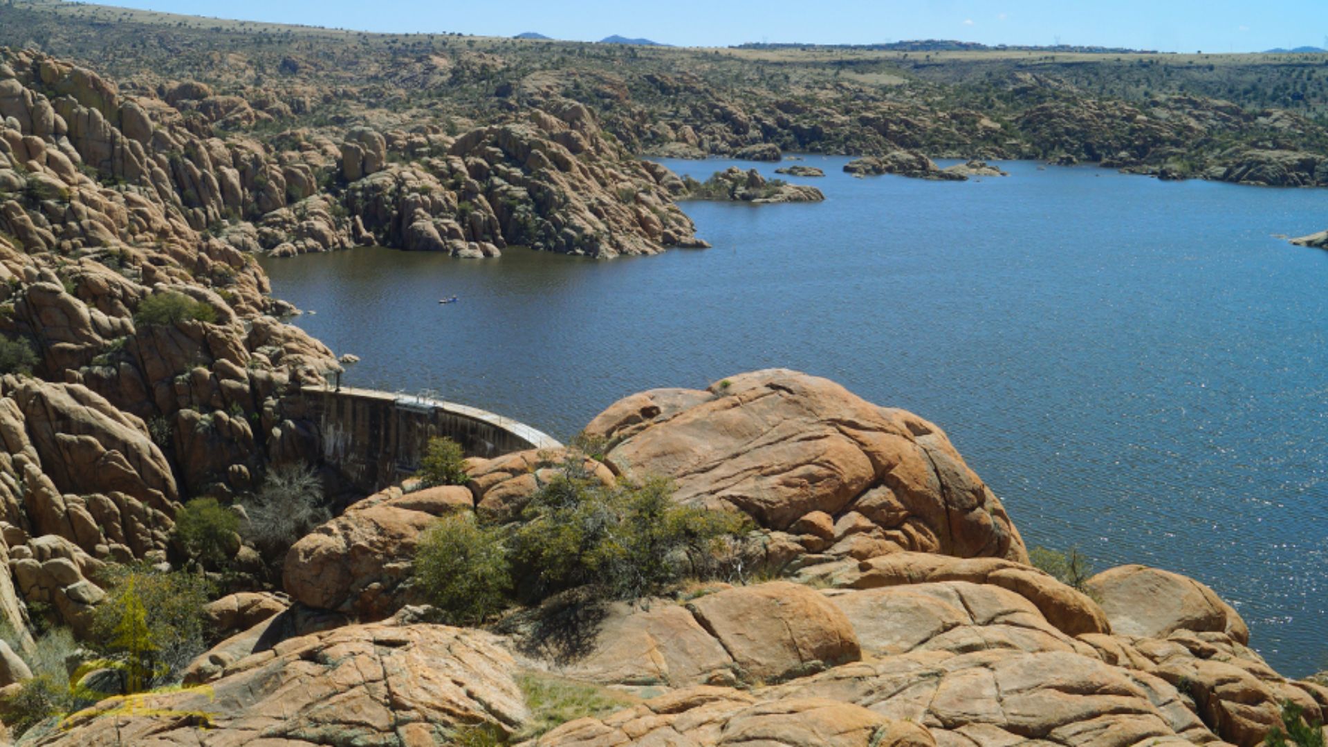 A vast expanse of water under a clear sky, reflecting light and surrounded by distant land.
