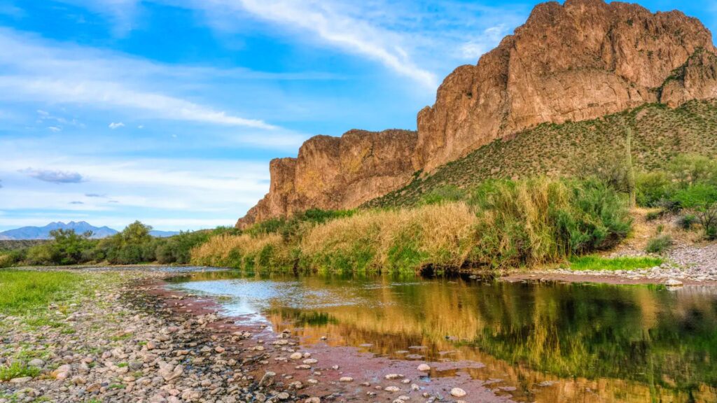 15 Best Weekend Trips From Phoenix You’ll Love A river winds through a rocky canyon surrounded by towering mountains under a clear blue sky.
