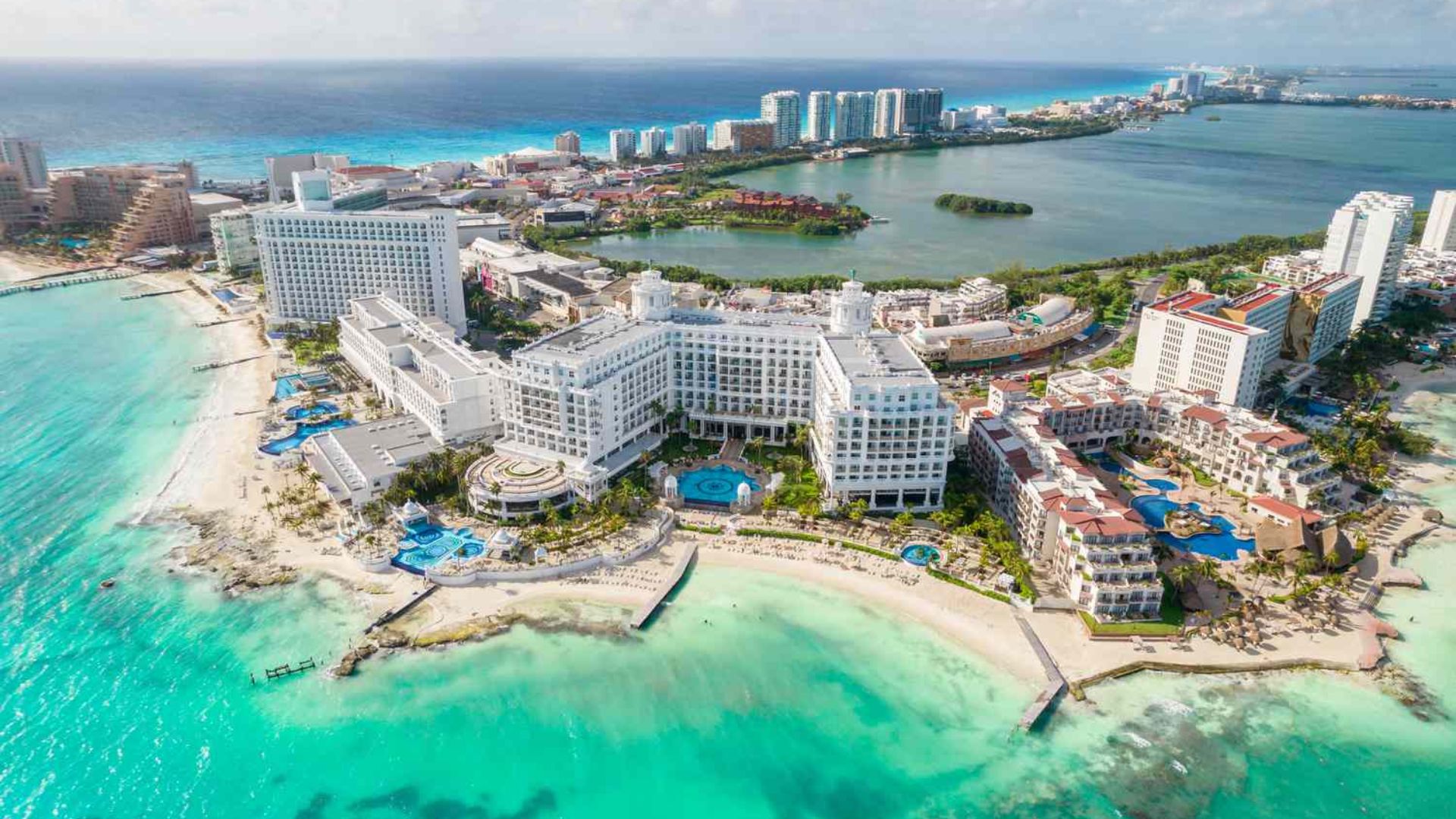 A scenic view of Cancun, Mexico, showcasing its beautiful beaches and vibrant blue waters under a clear sky.