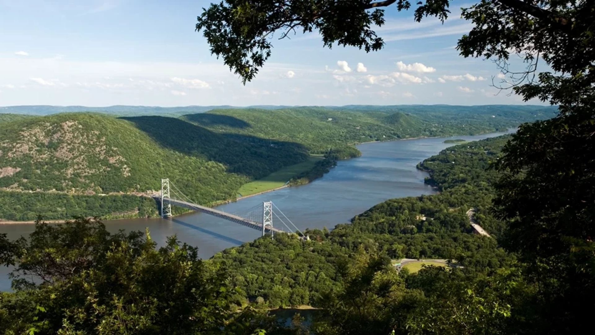 Scenic view from a hilltop overlooking a winding river surrounded by lush greenery under a clear blue sky.