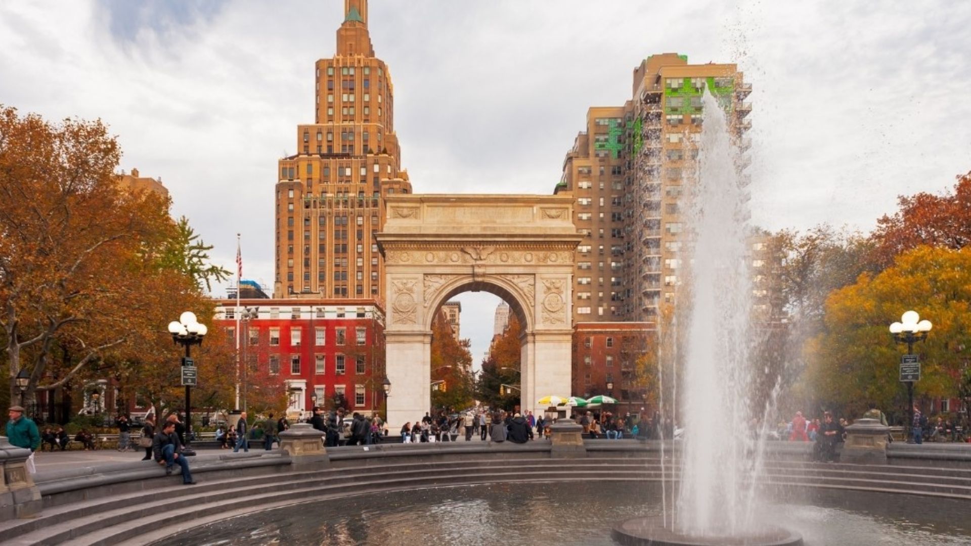 A fountain in the center of a bustling New York City square, surrounded by people and tall buildings.