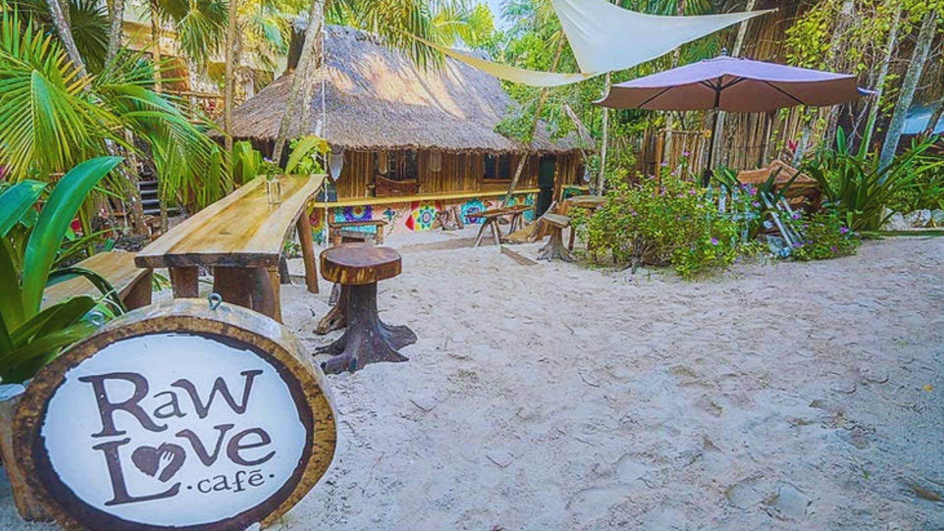 A cozy interior of Raw Love Cafe in Tulum, featuring wooden decor and plants, inviting patrons to enjoy healthy meals.