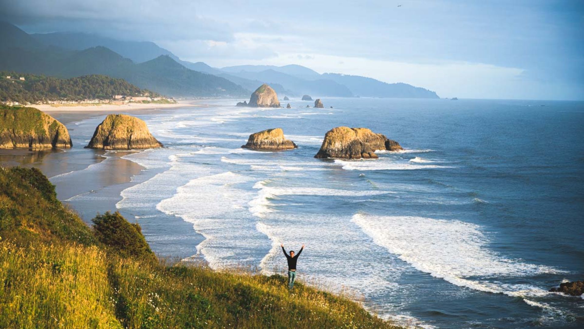 Haystack Rock rises majestically at Cannon Beach, Oregon, surrounded by sandy shores and gentle ocean waves.