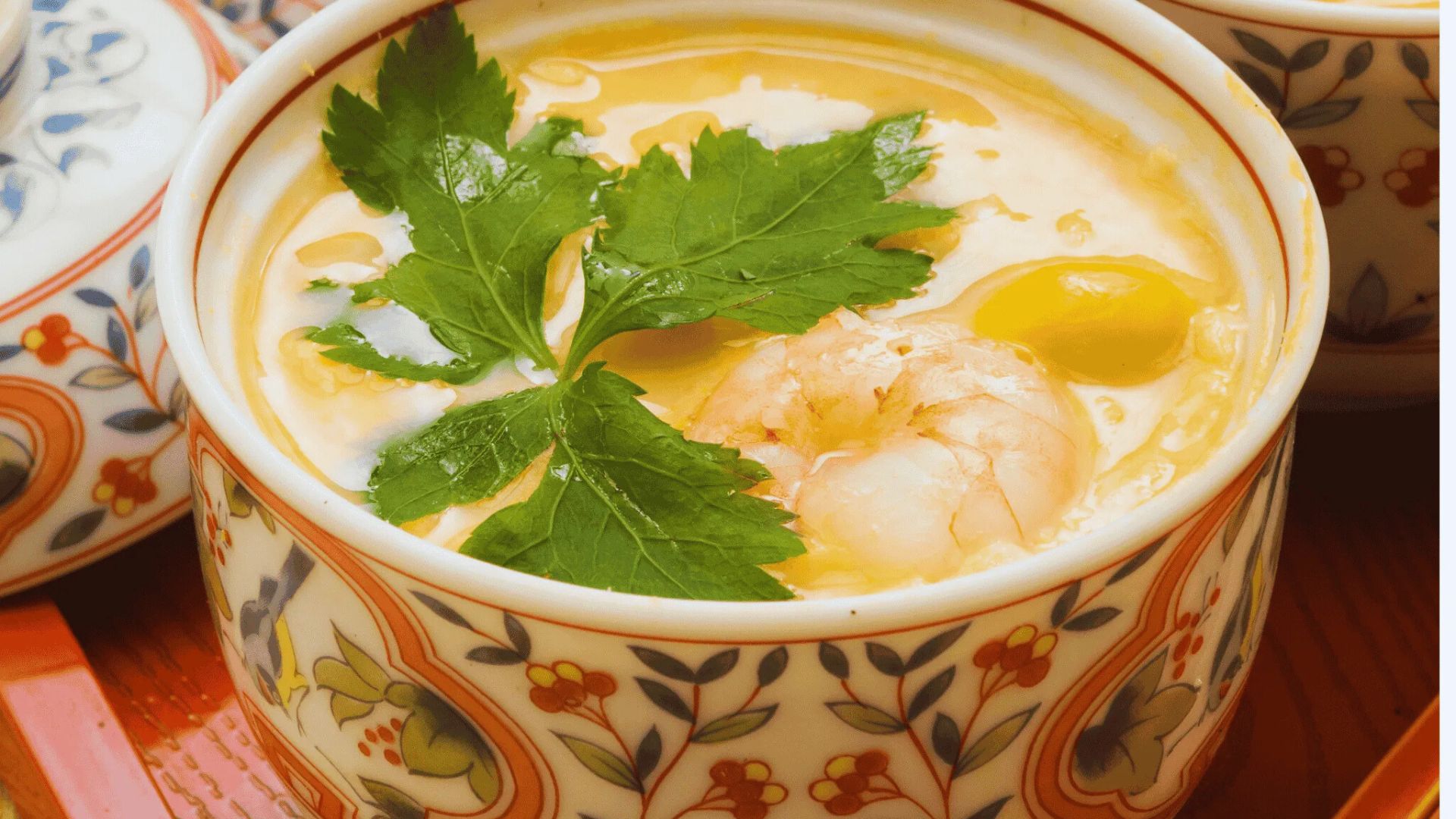A bowl of soup filled with shrimp and colorful vegetables, garnished for a vibrant presentation.