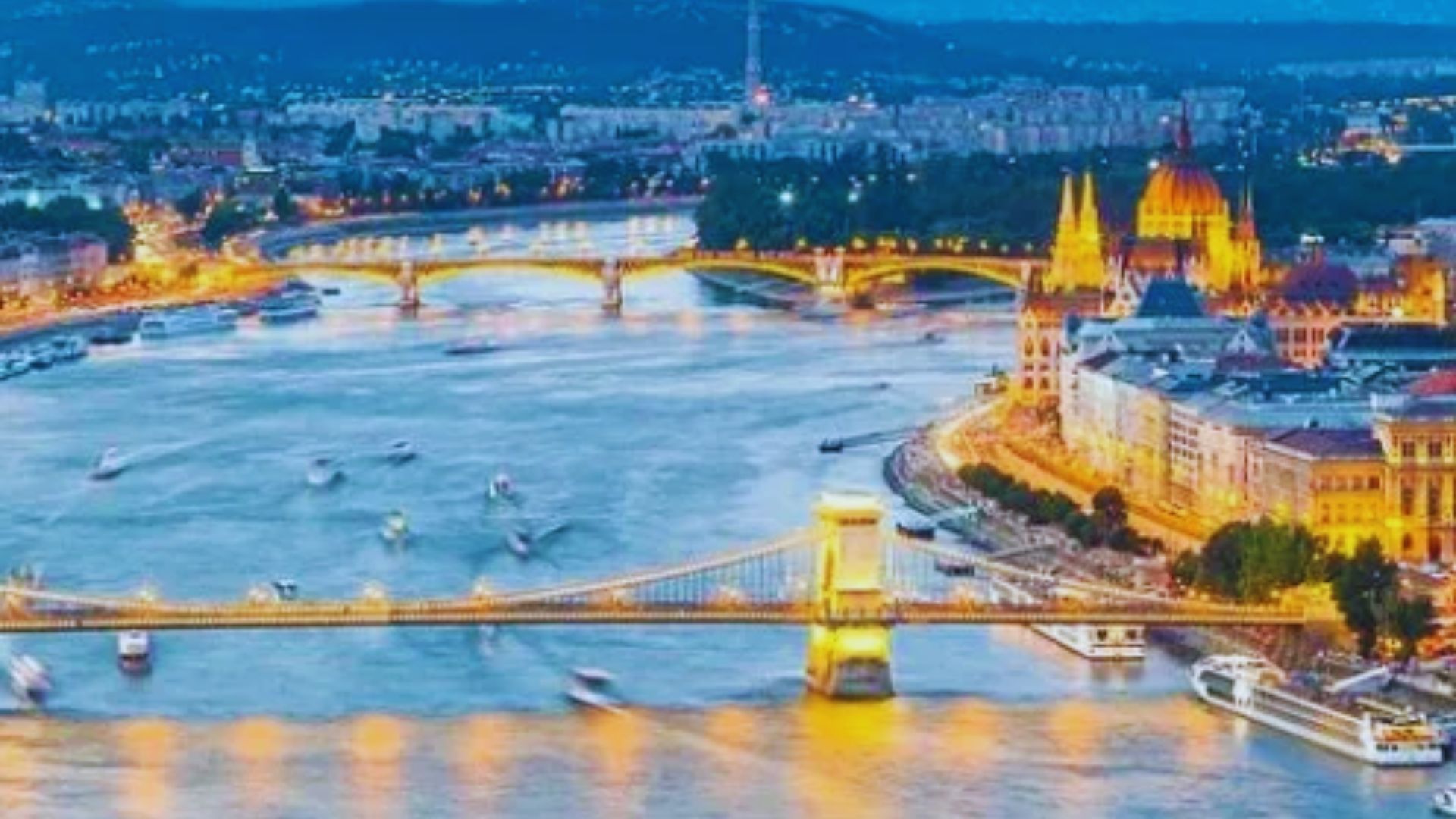 The illuminated Budapest skyline reflects on the Danube River at night, showcasing the city's stunning architecture.