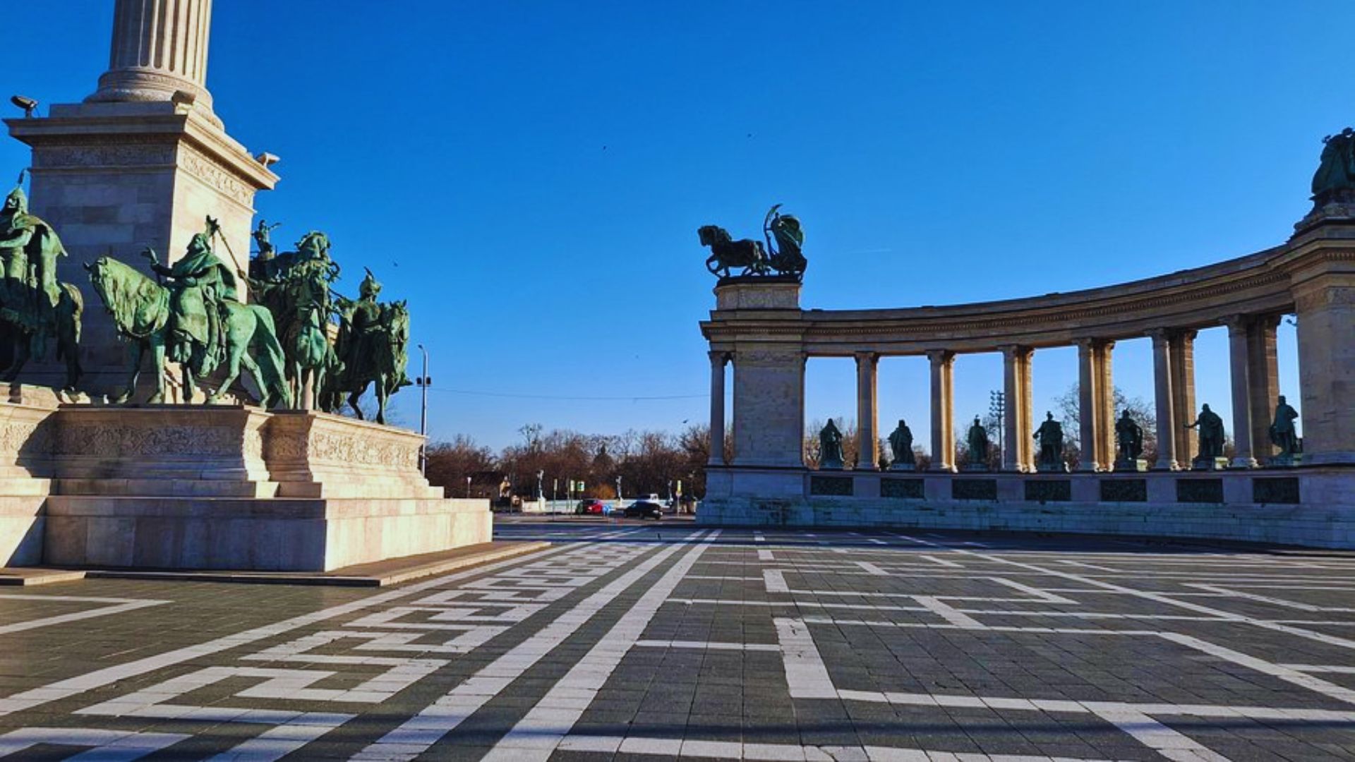 A large statue of a man on horseback stands prominently in front of a historic building.