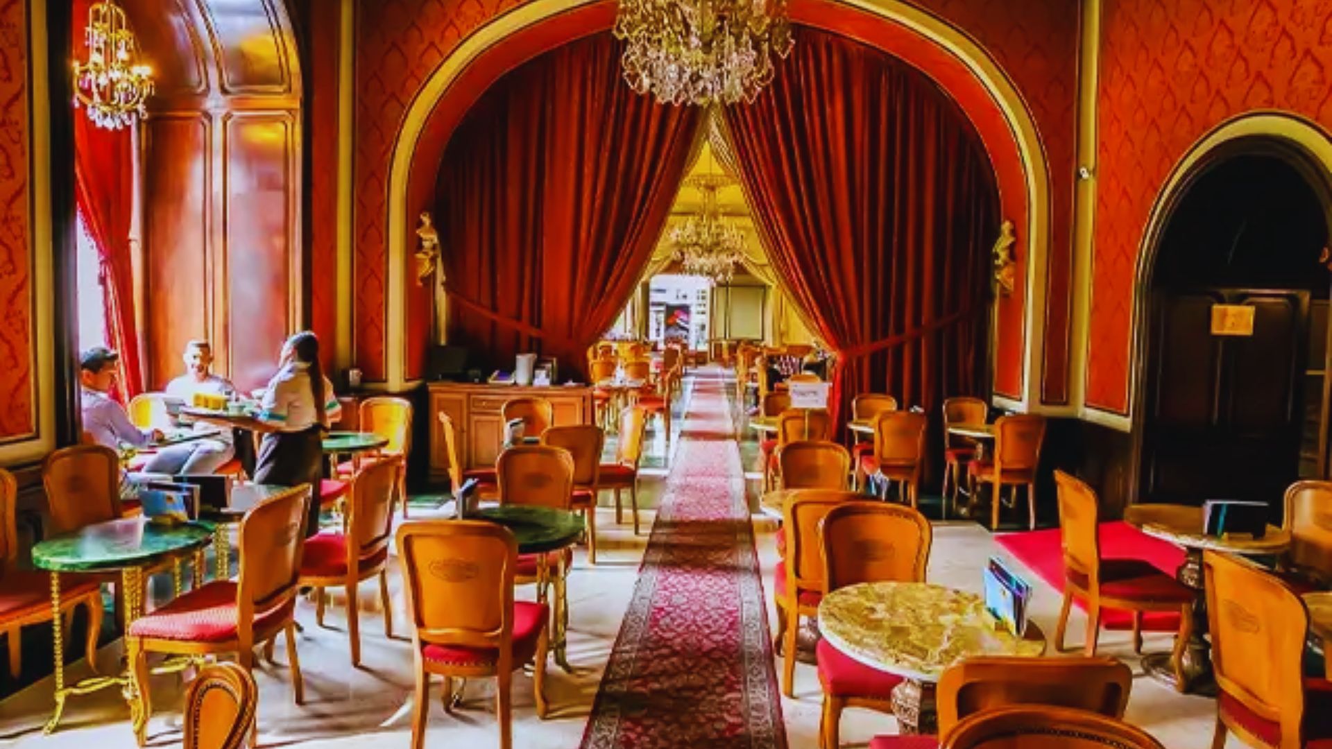 The interior of a restaurant featuring elegant red curtains and ornate gold trim, creating a warm and inviting atmosphere.