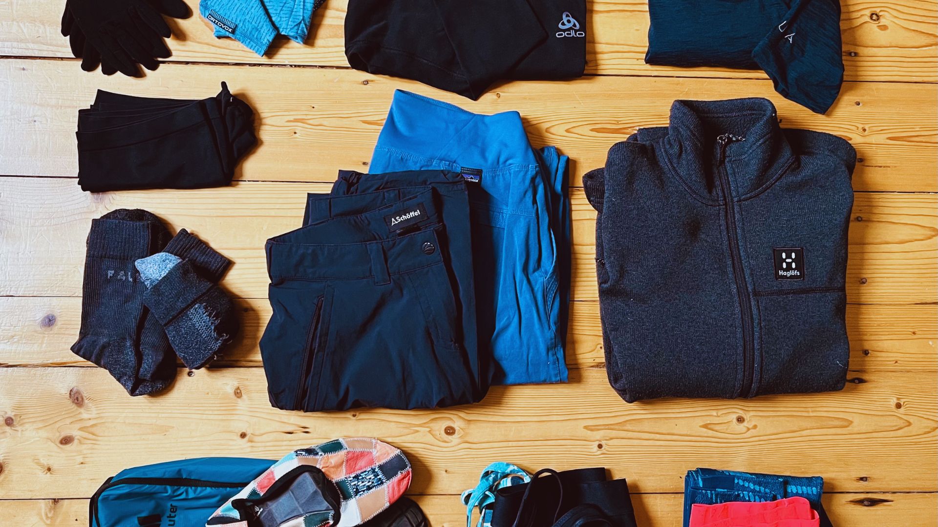 A collection of clothing and accessories spread out on a wooden floor, featuring various styles and vibrant colors.