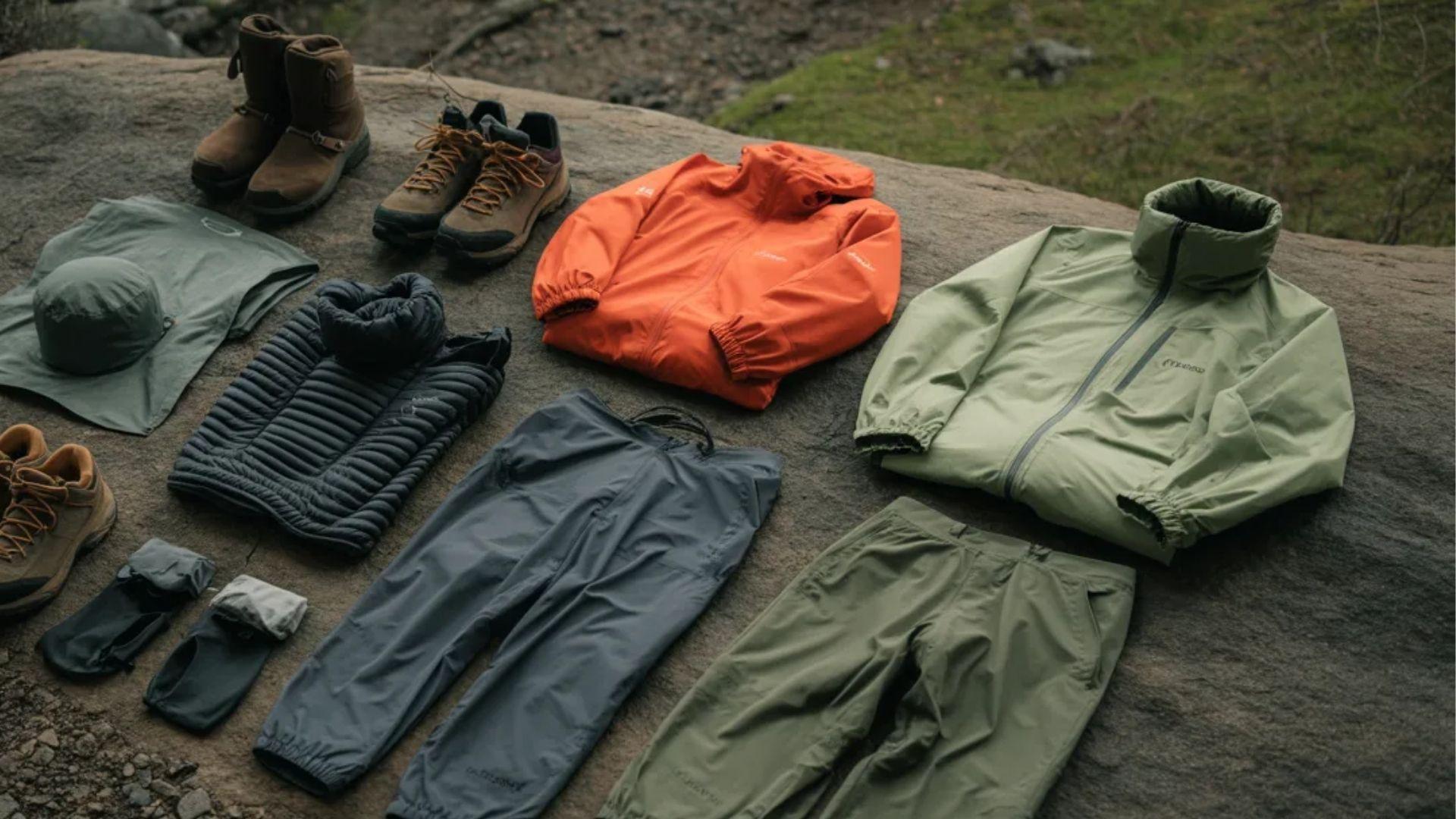 A selection of outdoor clothing and gear displayed on a rock, showcasing various items for hiking and camping activities.