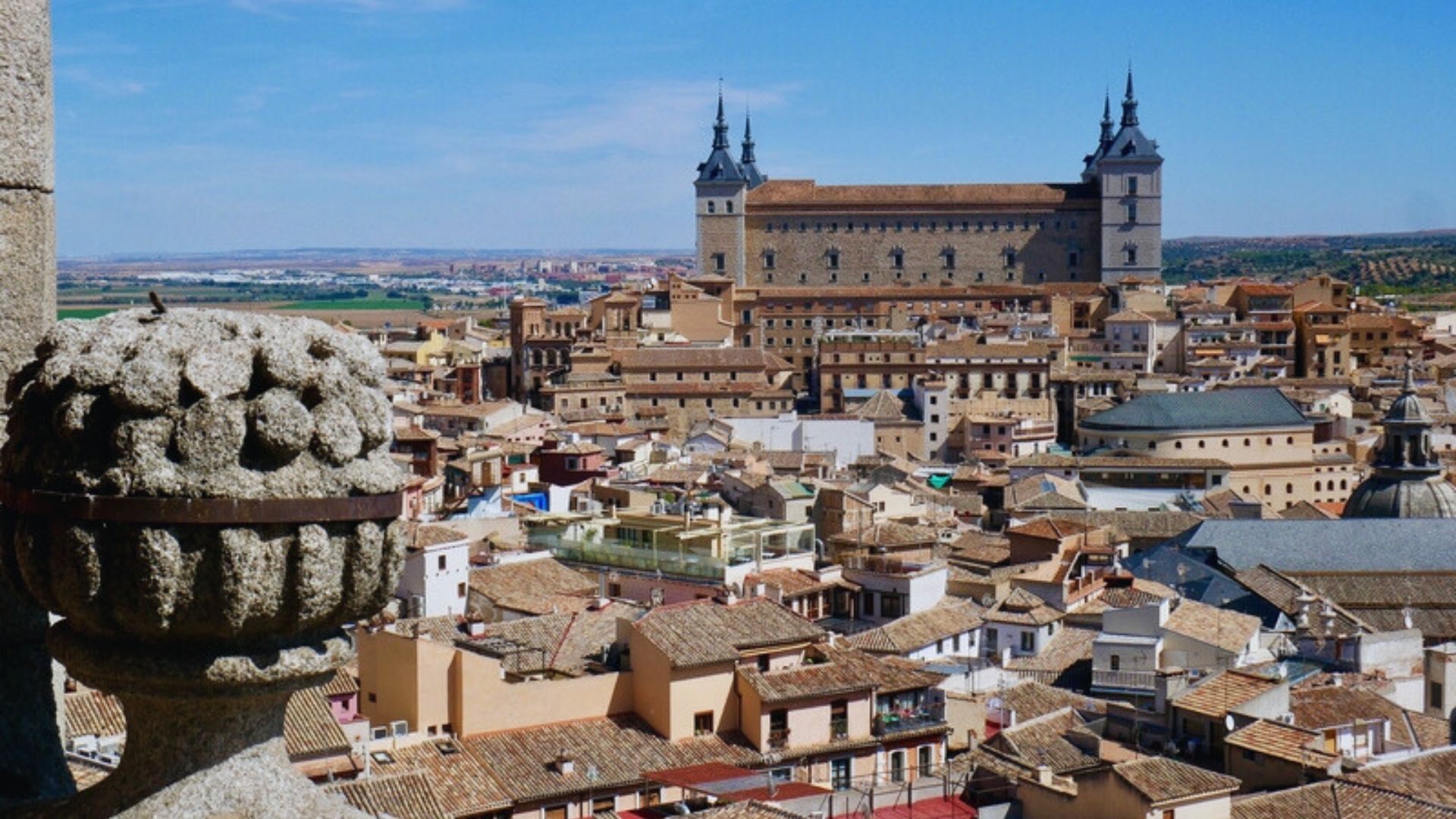 A panoramic view of Toledo cityscape from the top of a tower, showcasing historic buildings and the surrounding landscape.