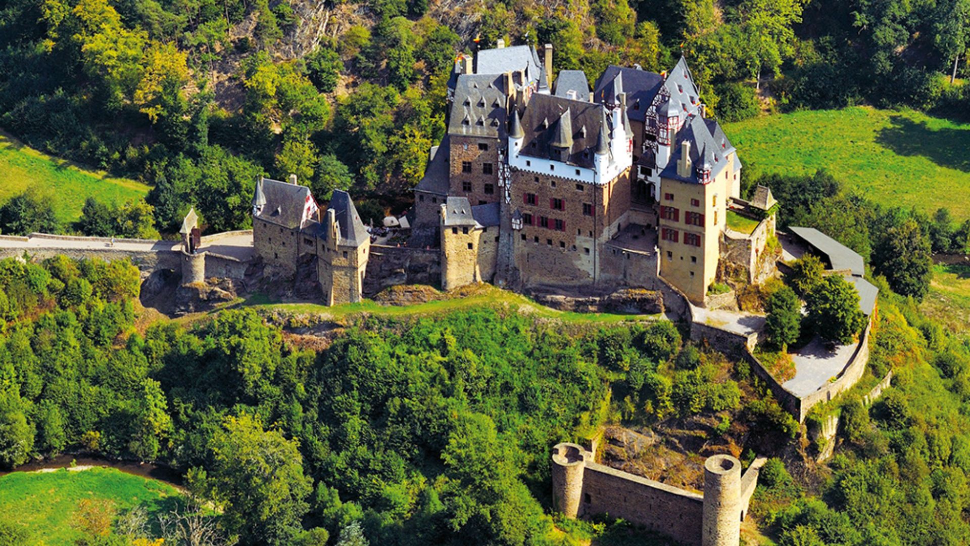 A majestic castle nestled among vibrant green trees, creating a picturesque and serene landscape.