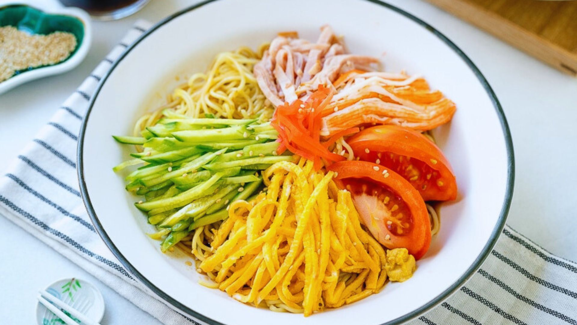 A bowl of noodles topped with colorful vegetables and pieces of meat, showcasing a delicious meal.