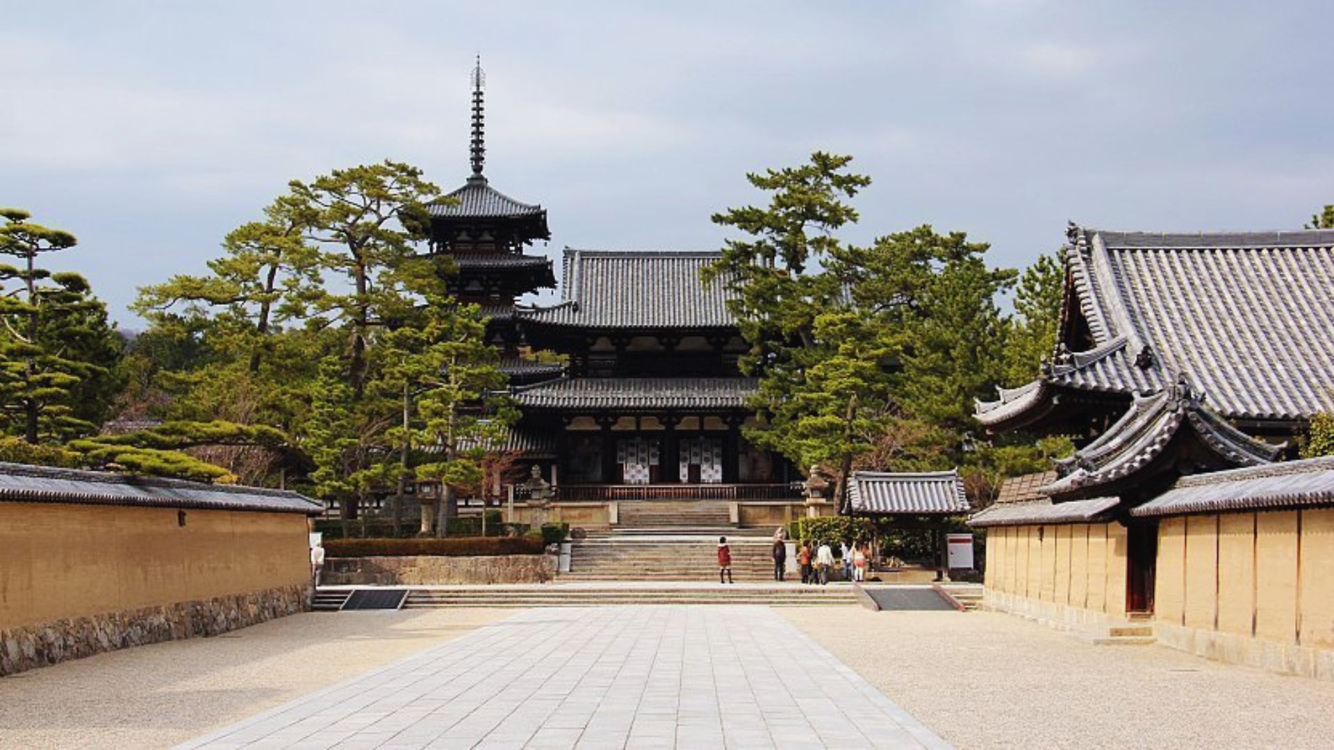 A serene forest path winding through trees, leading to a distant temple nestled among the greenery.