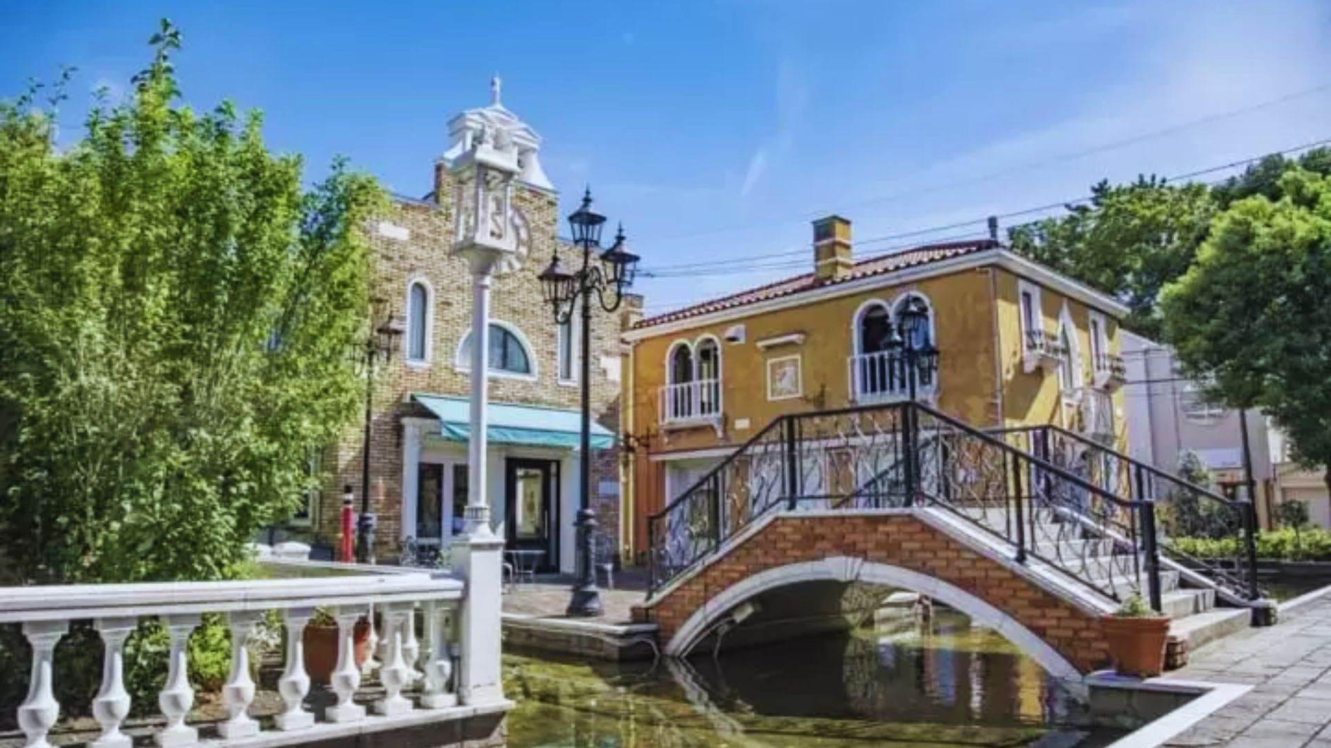 A scenic canal featuring a bridge, with a building visible in the background under a clear blue sky.