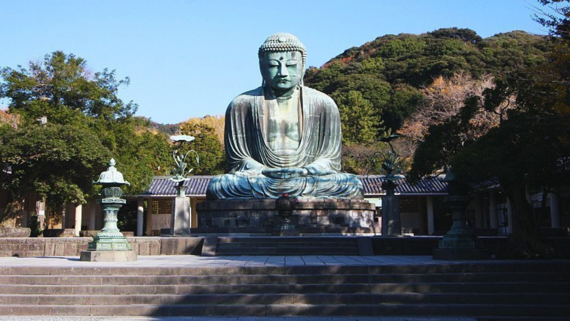 A large Buddha statue stands prominently in front of a building, showcasing intricate details and serene expression.