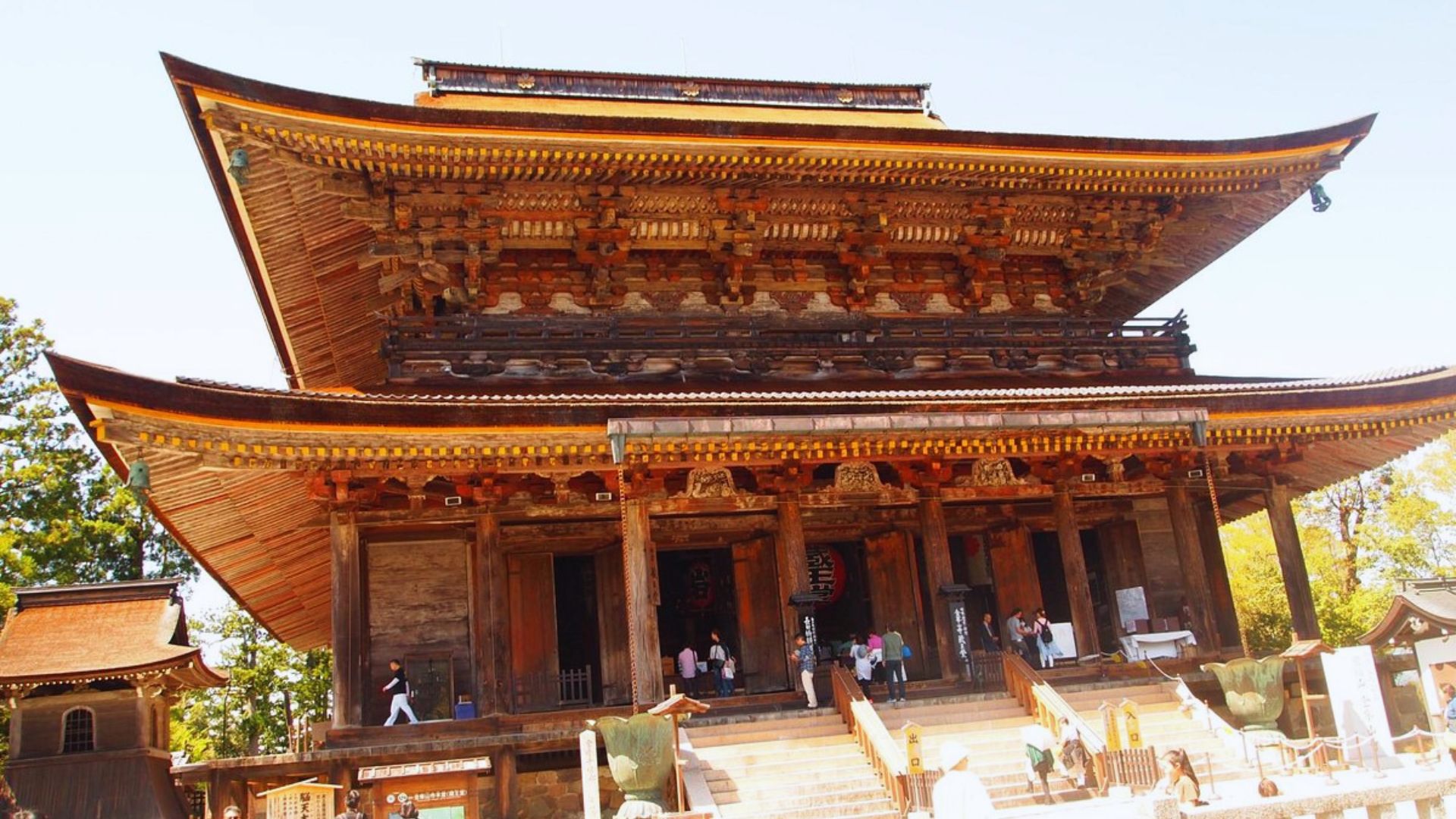 A large wooden building surrounded by numerous people walking around it, creating a lively atmosphere.