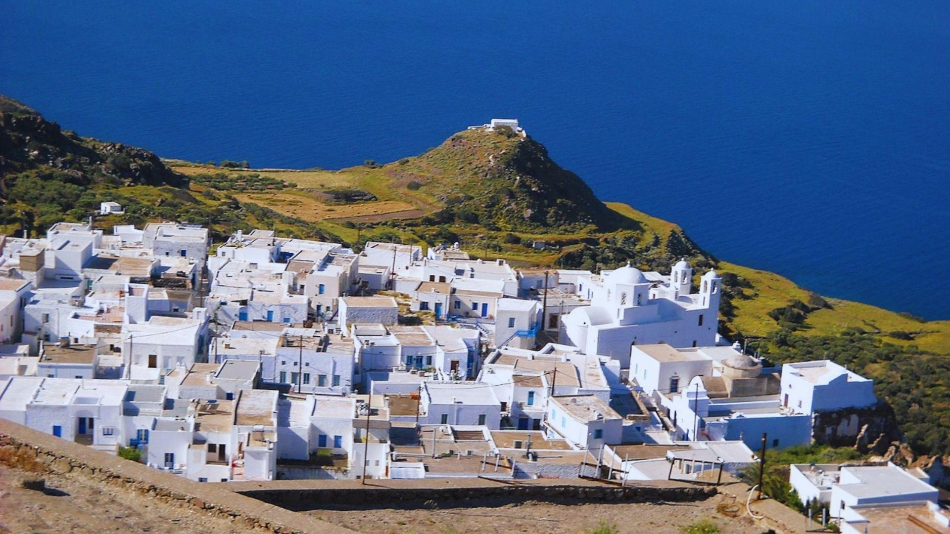 A scenic view of a white village perched along a picturesque coastline under a clear blue sky.