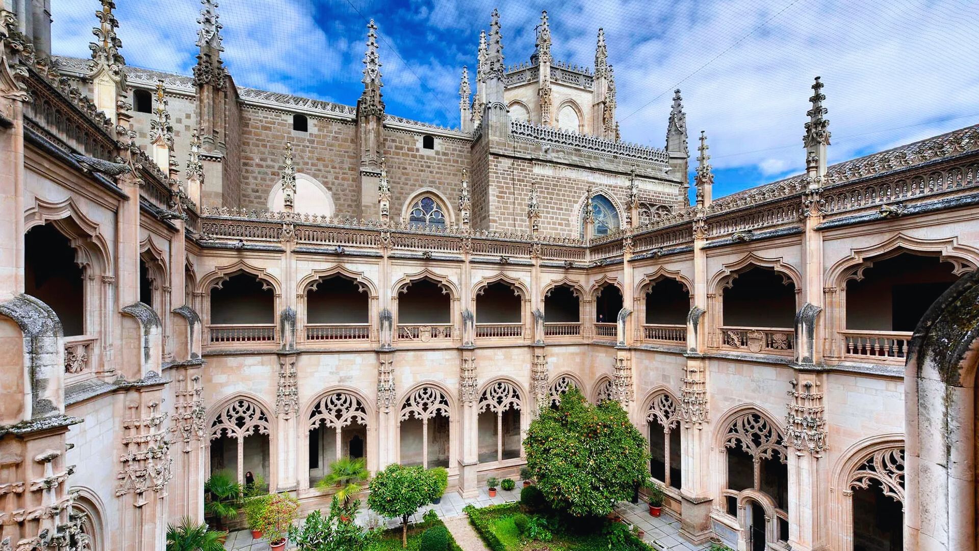 The courtyard of Seville Cathedral, featuring intricate architecture and lush greenery, inviting visitors to explore its beauty.