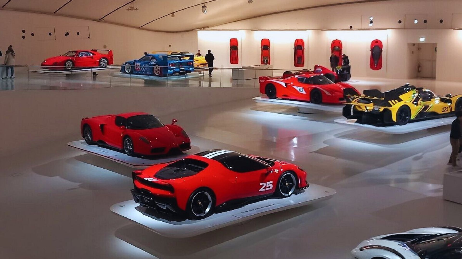 A room showcasing multiple red sports cars, highlighting their sleek designs and vibrant colors.