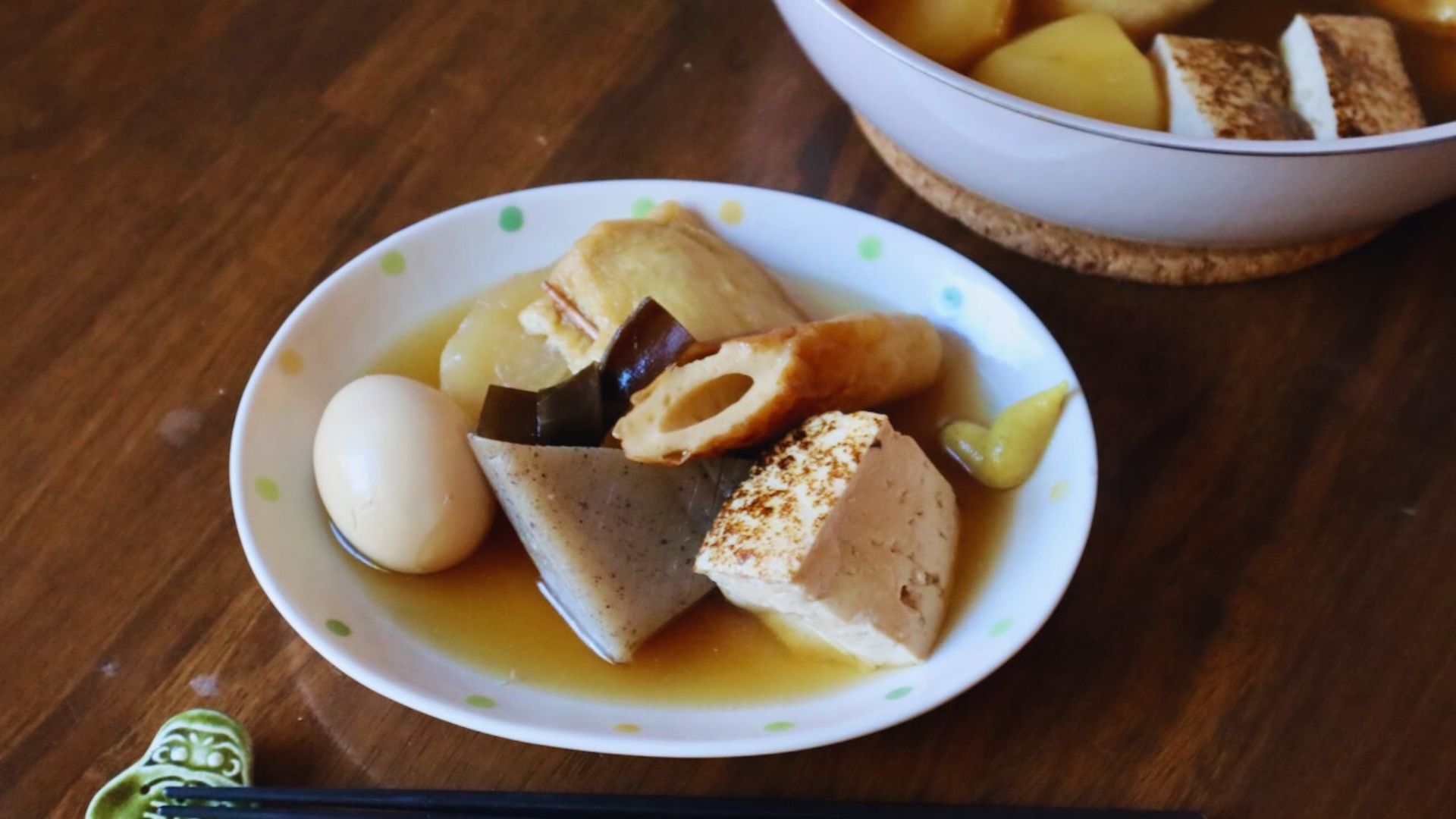A bowl of steaming soup with chopsticks resting on the side and a spoon placed nearby.