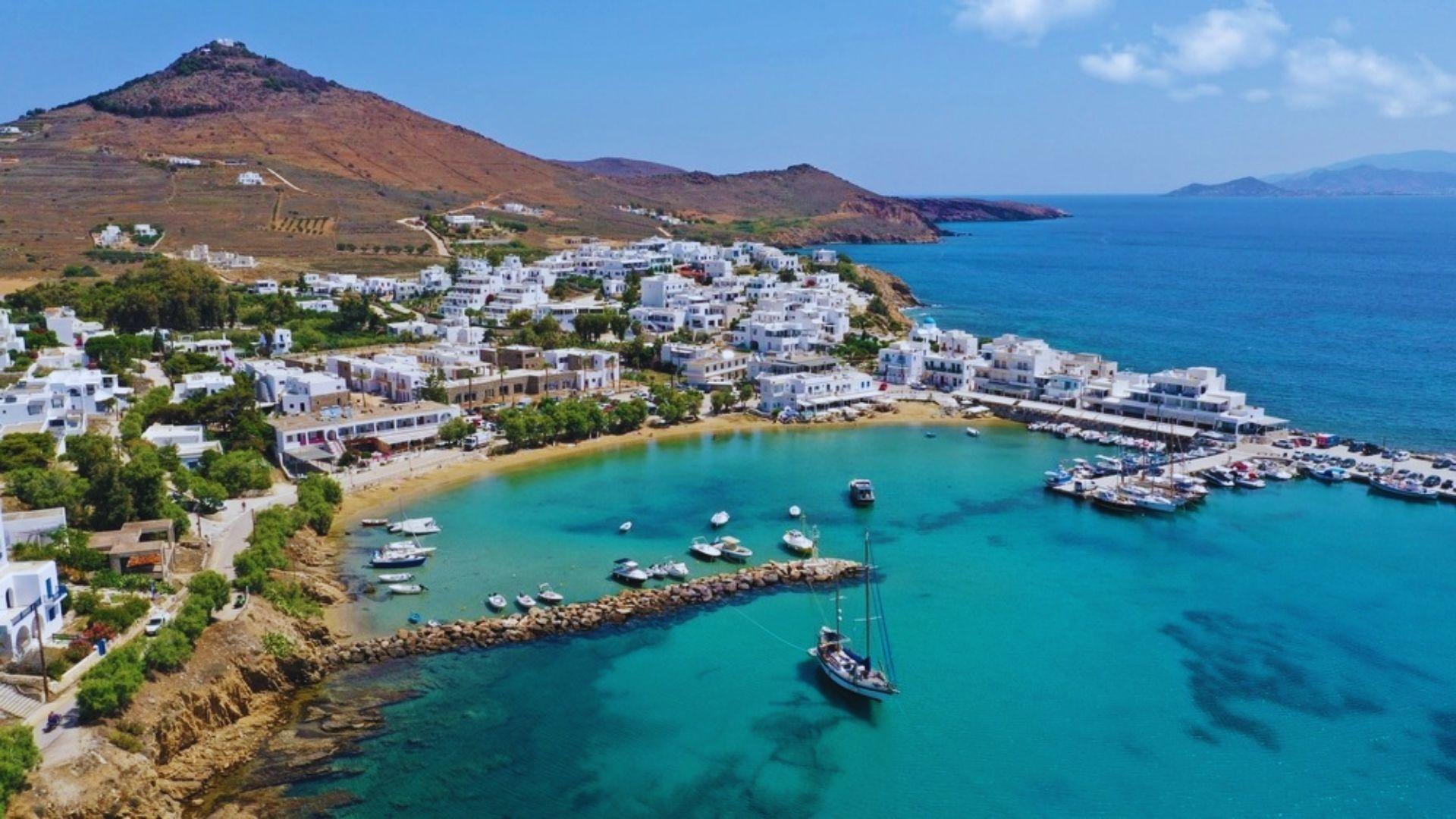 Scenic view of Mykonos island featuring white buildings and blue waters under a clear sky.