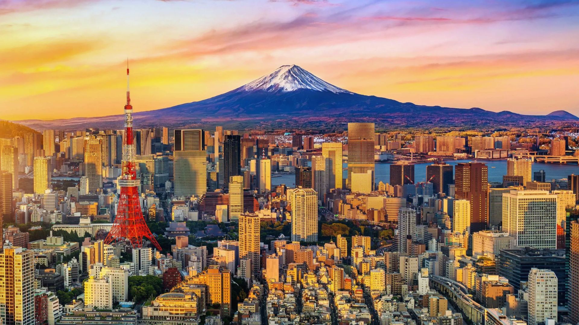 Tokyo cityscape featuring skyscrapers with Mount Fuji majestically rising in the background under a clear blue sky.
