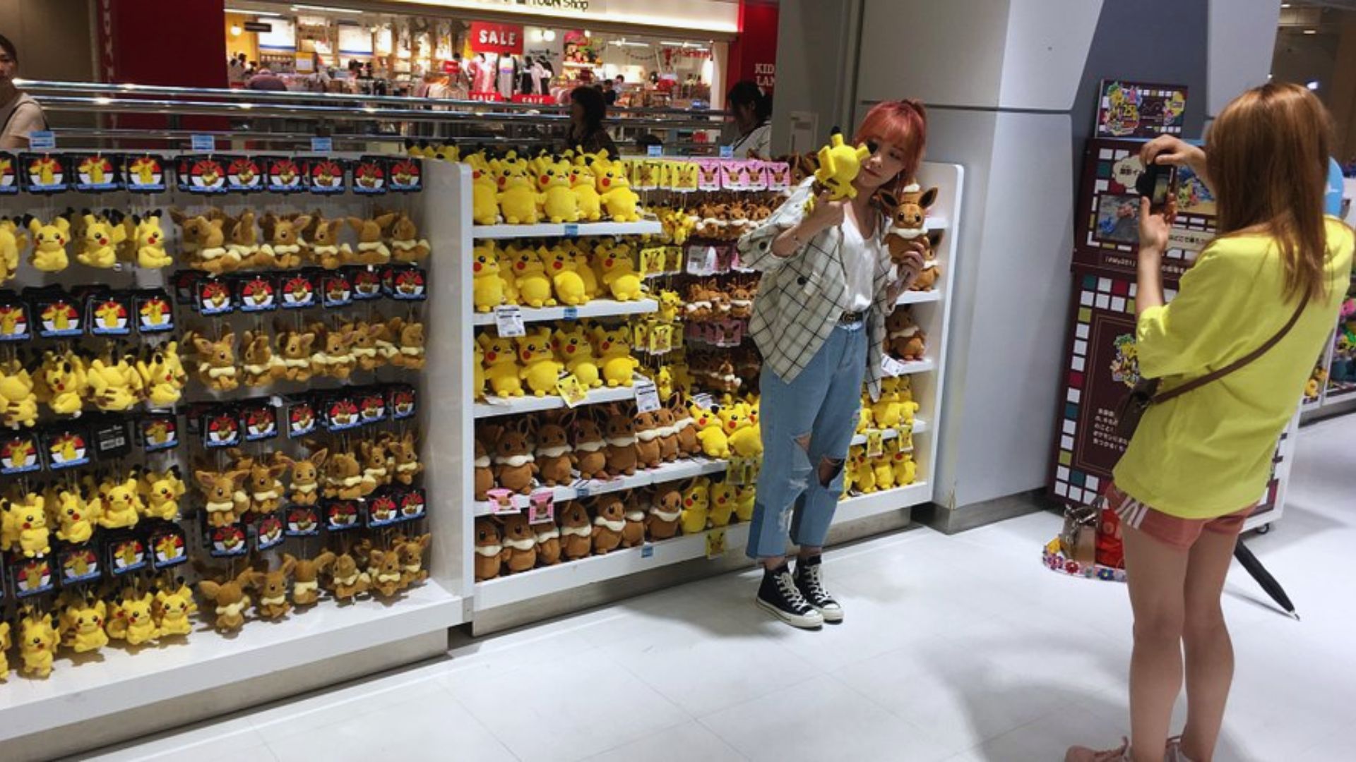 A woman captures an image of a plush toy in a store, focusing on the colorful details.