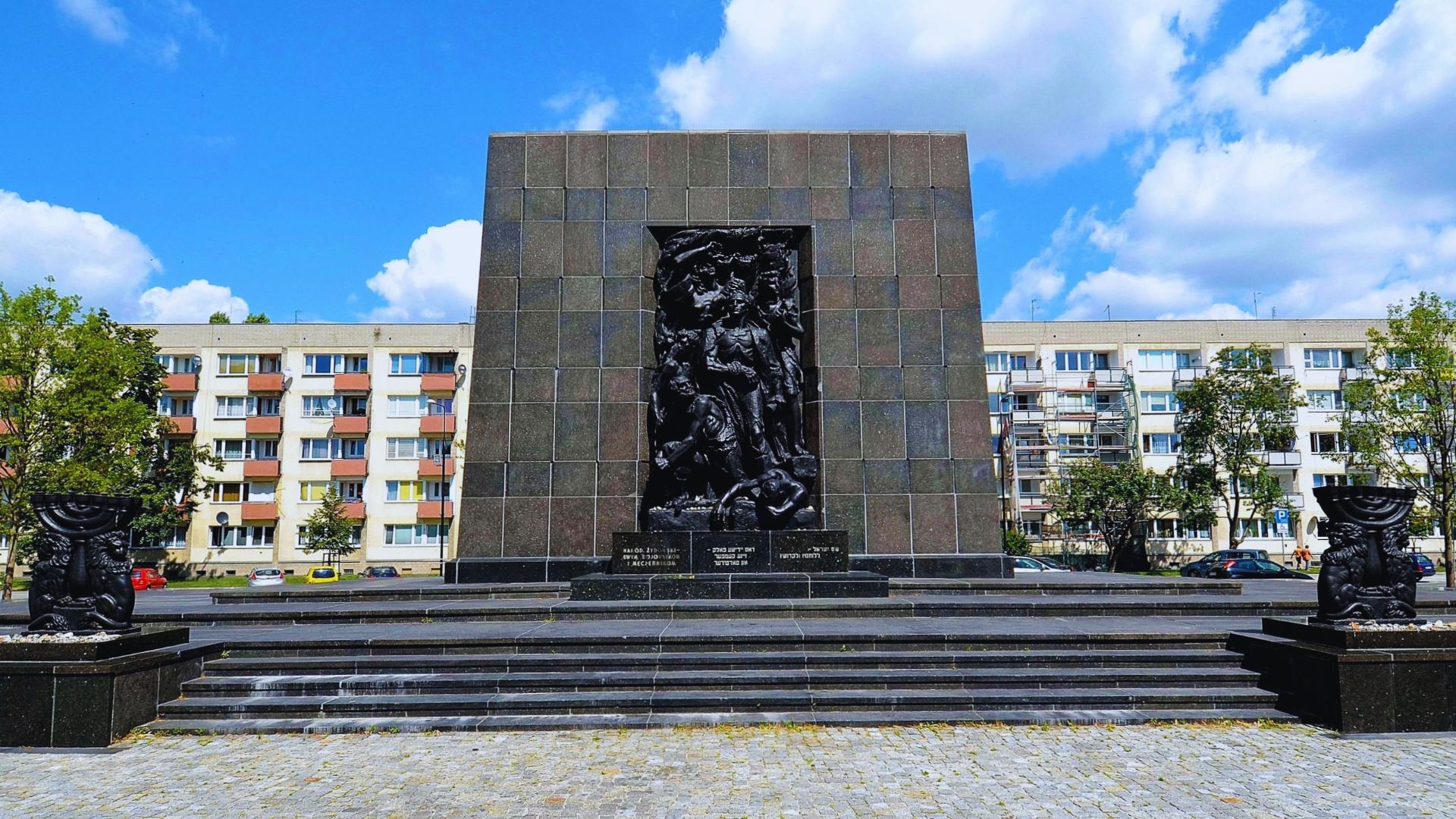 A monument stands in front of a building adorned with statues, showcasing intricate designs and historical significance.
