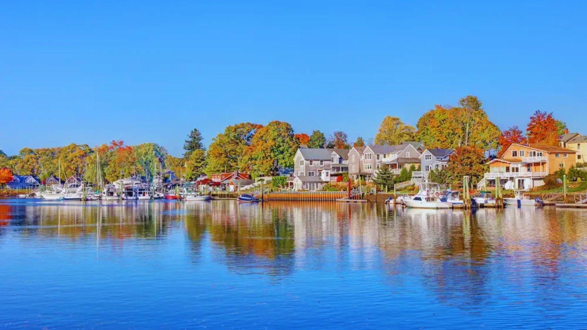 A scenic waterfront view featuring houses along the shore and boats moored in the water.