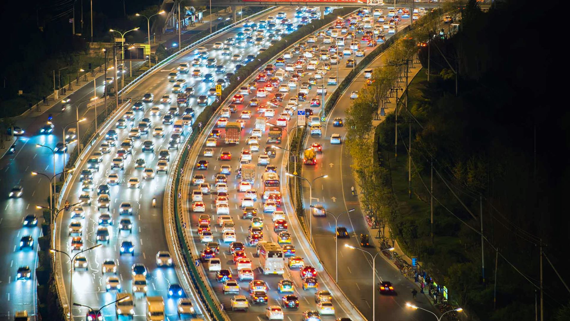 Traffic jam on a highway at night, with rows of cars illuminated by headlights and streetlights.