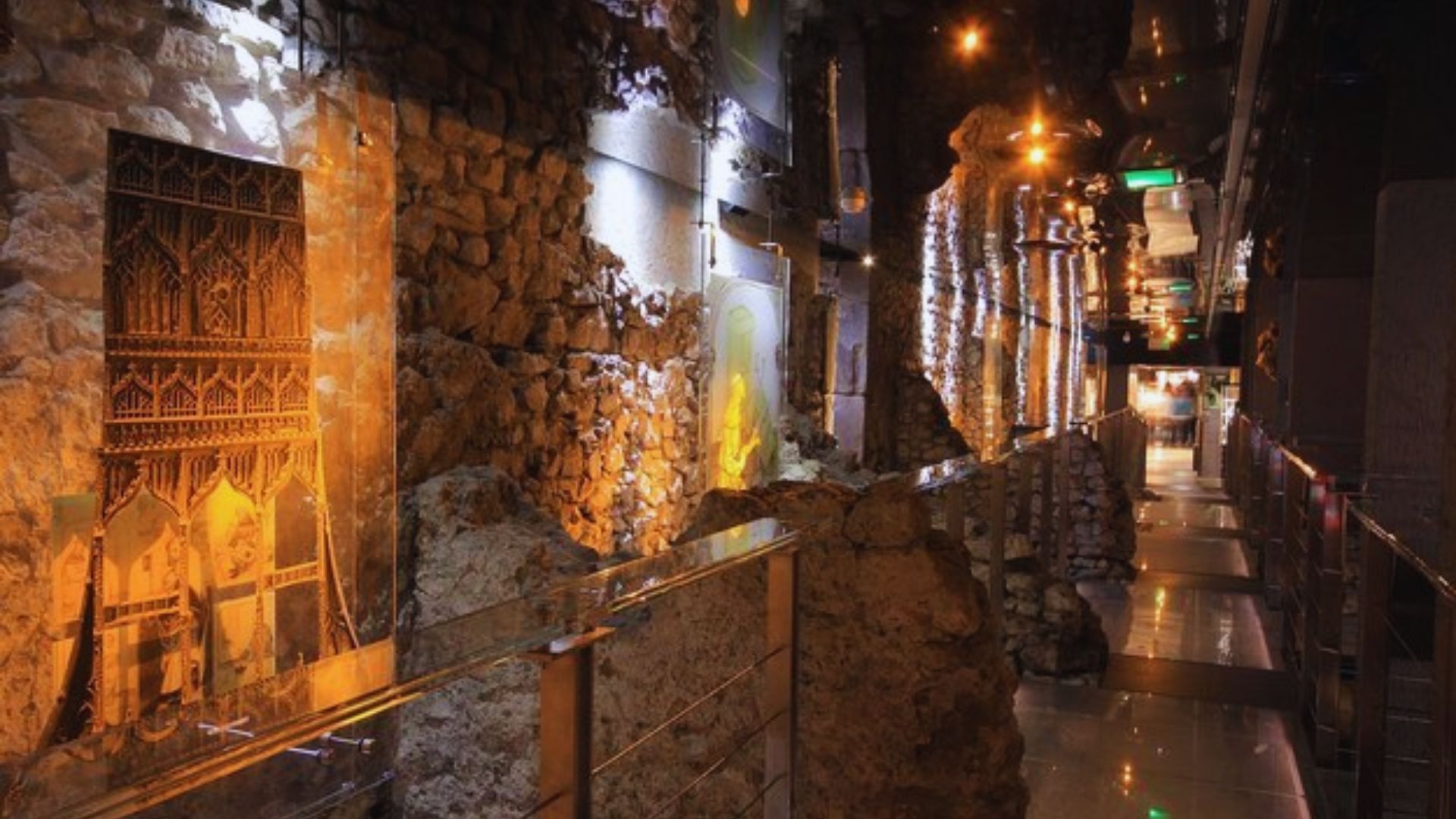 A walkway featuring stone walls and a softly illuminated ceiling, creating a warm and inviting atmosphere.