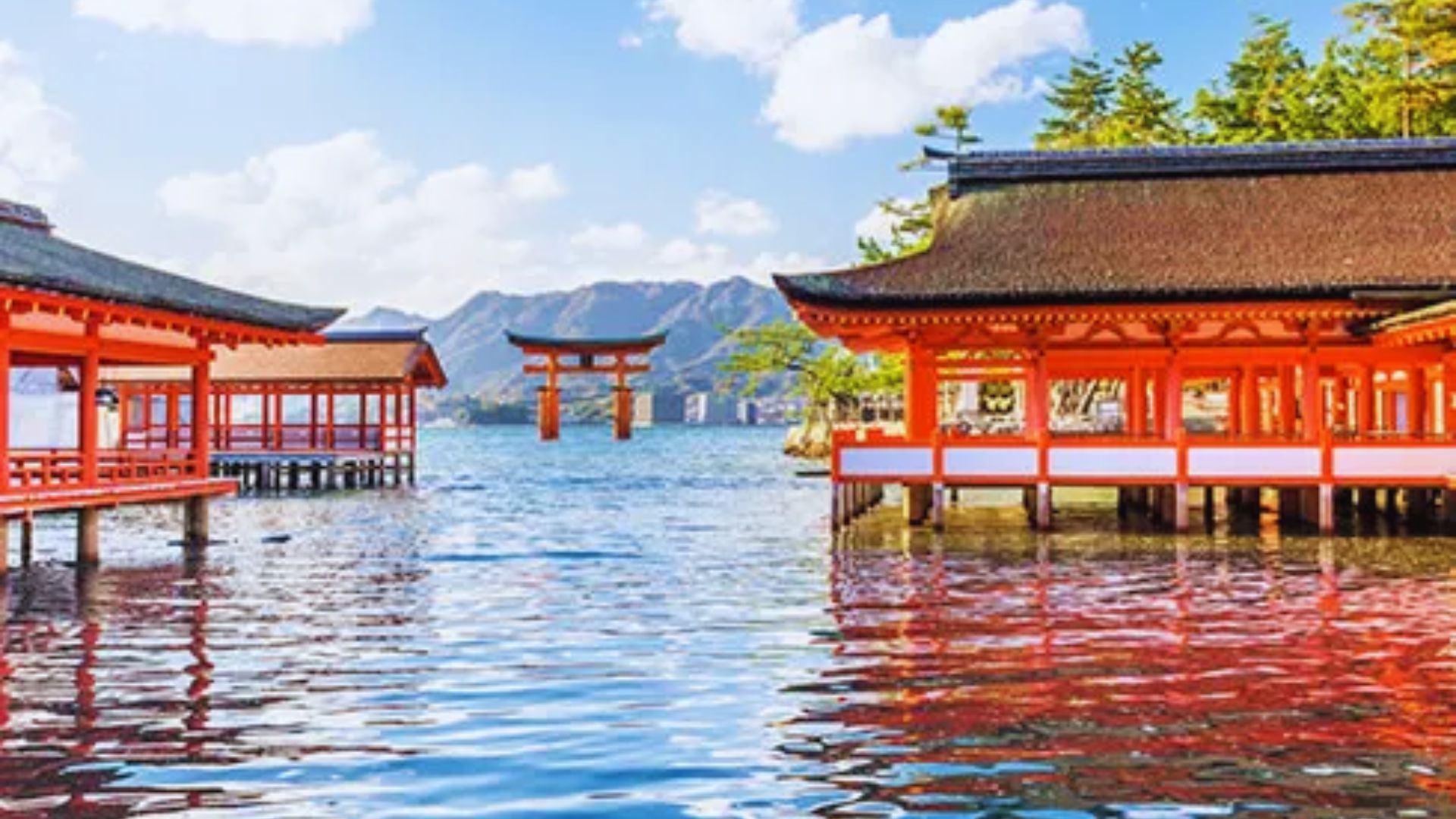 A serene Japanese pagoda reflected in calm water, surrounded by lush greenery and a clear blue sky.