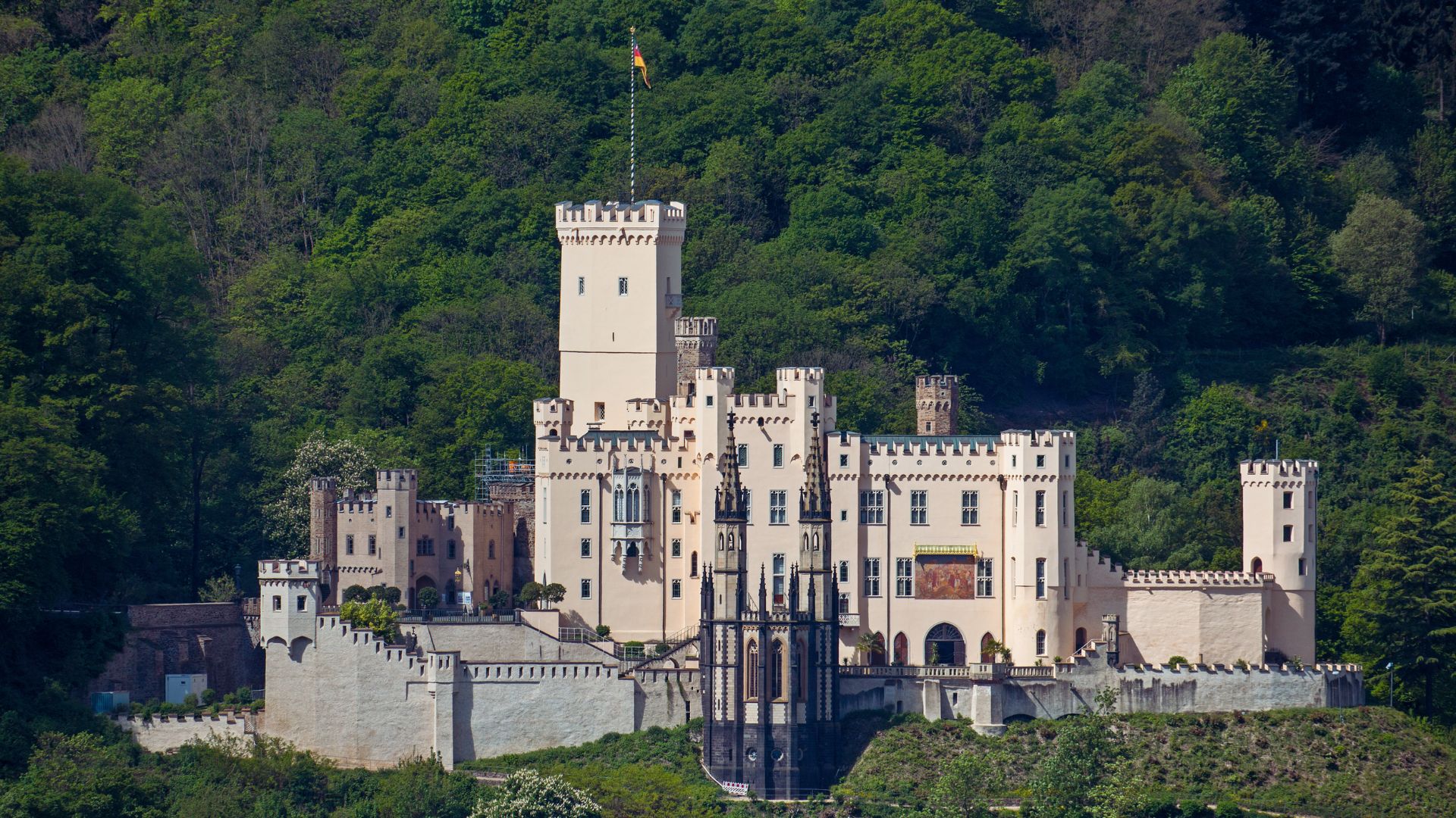 A castle perched atop a hill, encircled by lush green trees, creating a picturesque landscape.
