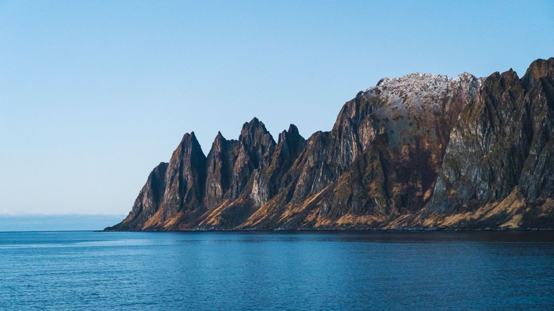 Tall, rugged mountains rise sharply against the sky, showcasing their rocky terrain and majestic peaks.
