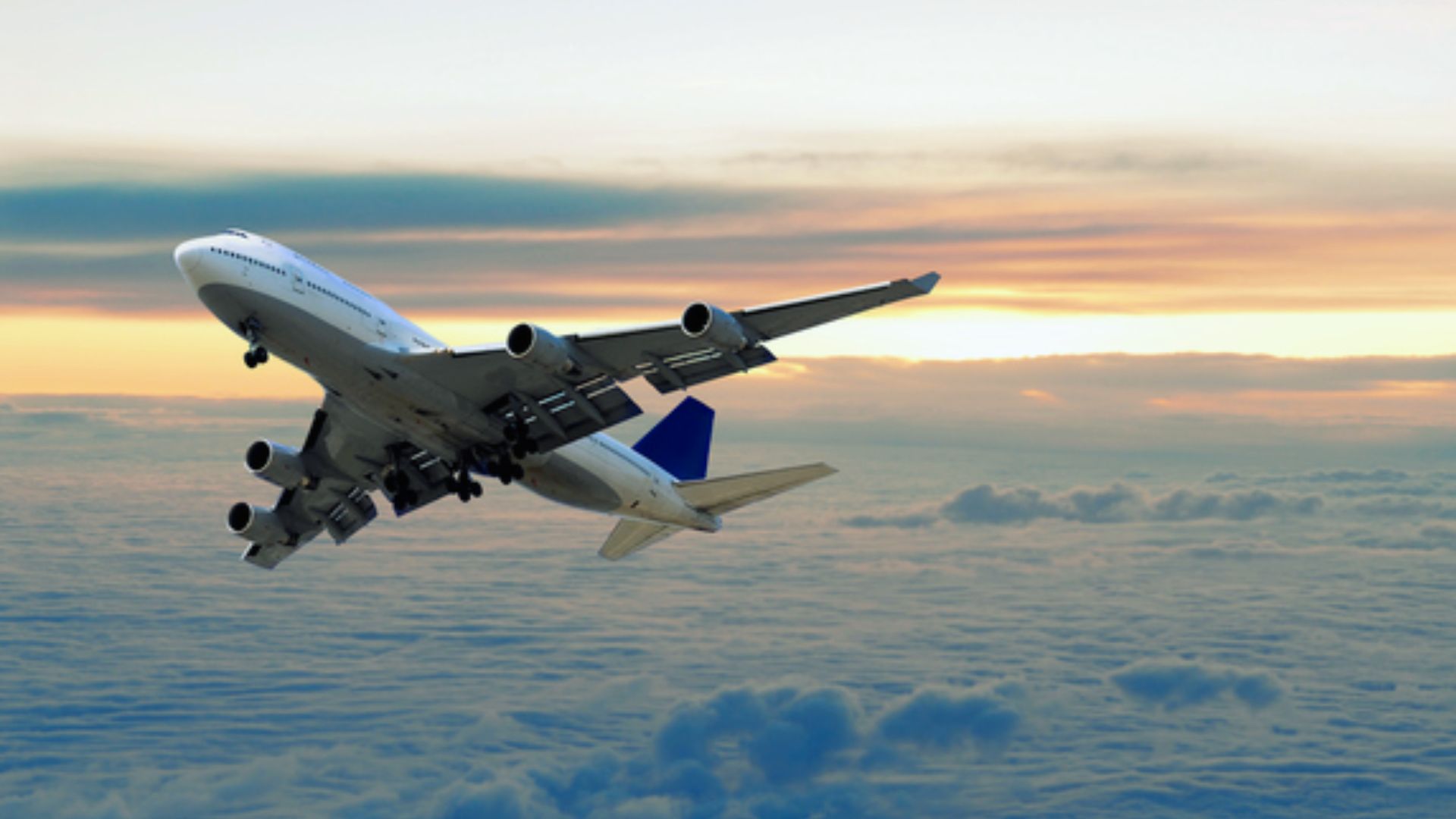 A large passenger jet soaring through a clear blue sky, showcasing its wings and fuselage against the backdrop of clouds.