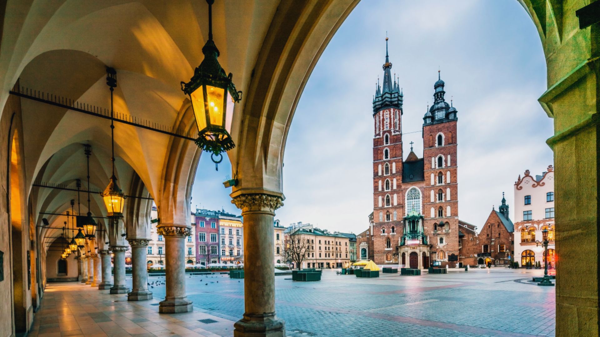 A bustling city square in Krakow, Poland, featuring historic buildings, outdoor cafes, and people enjoying the vibrant atmosphere.