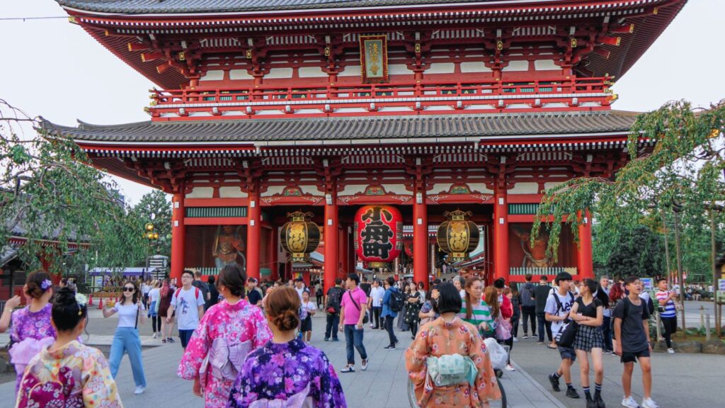 A group of people walking in front of a large temple, showcasing its architectural details and cultural significance.