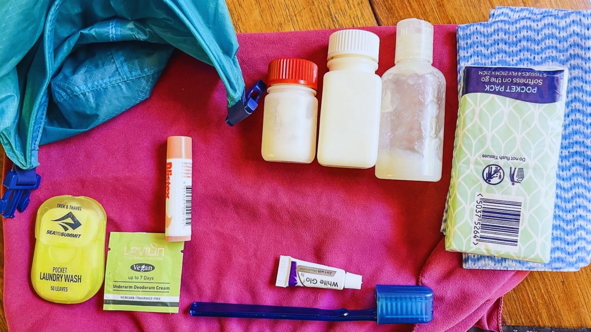A pink bag filled with multiple tubes of toothpaste and a toothbrush, arranged neatly for dental care.