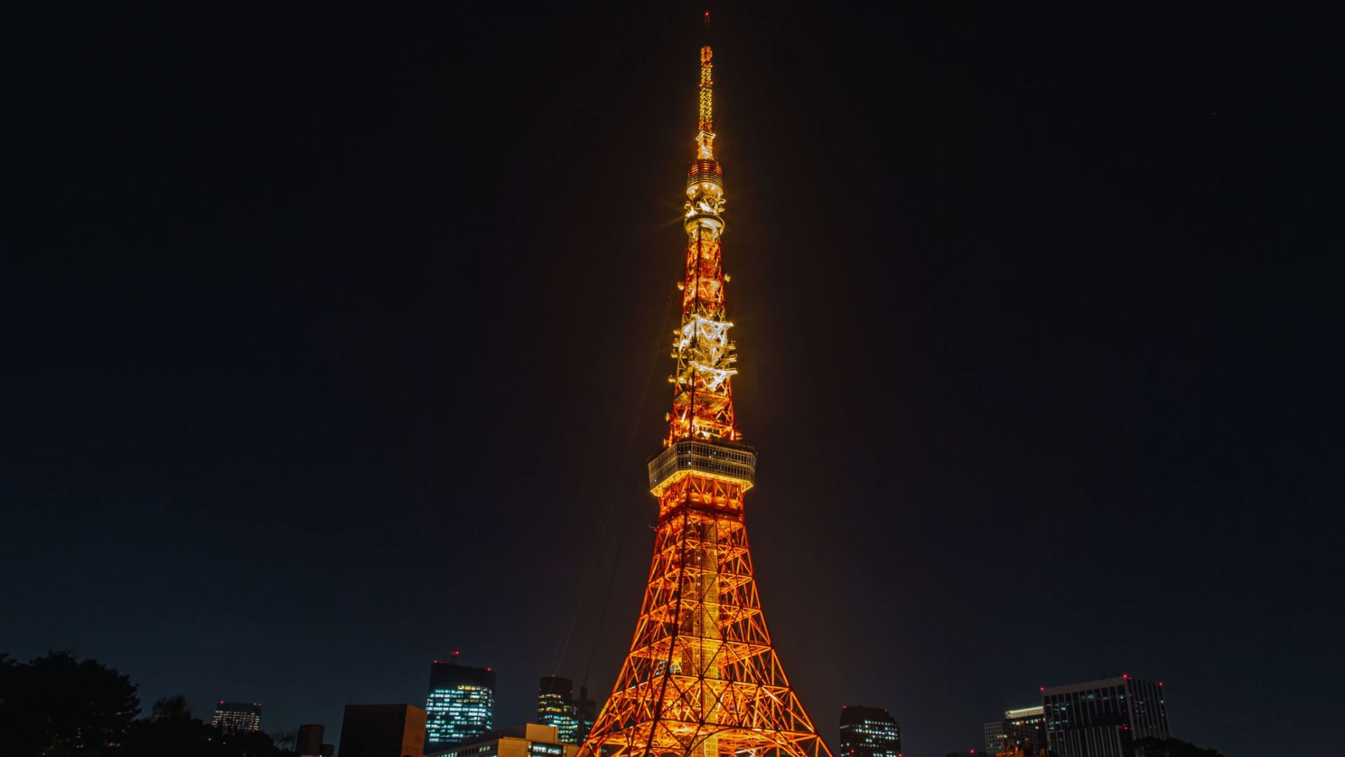 Tokyo Tower illuminated at night, showcasing its iconic structure against a dark sky filled with stars.