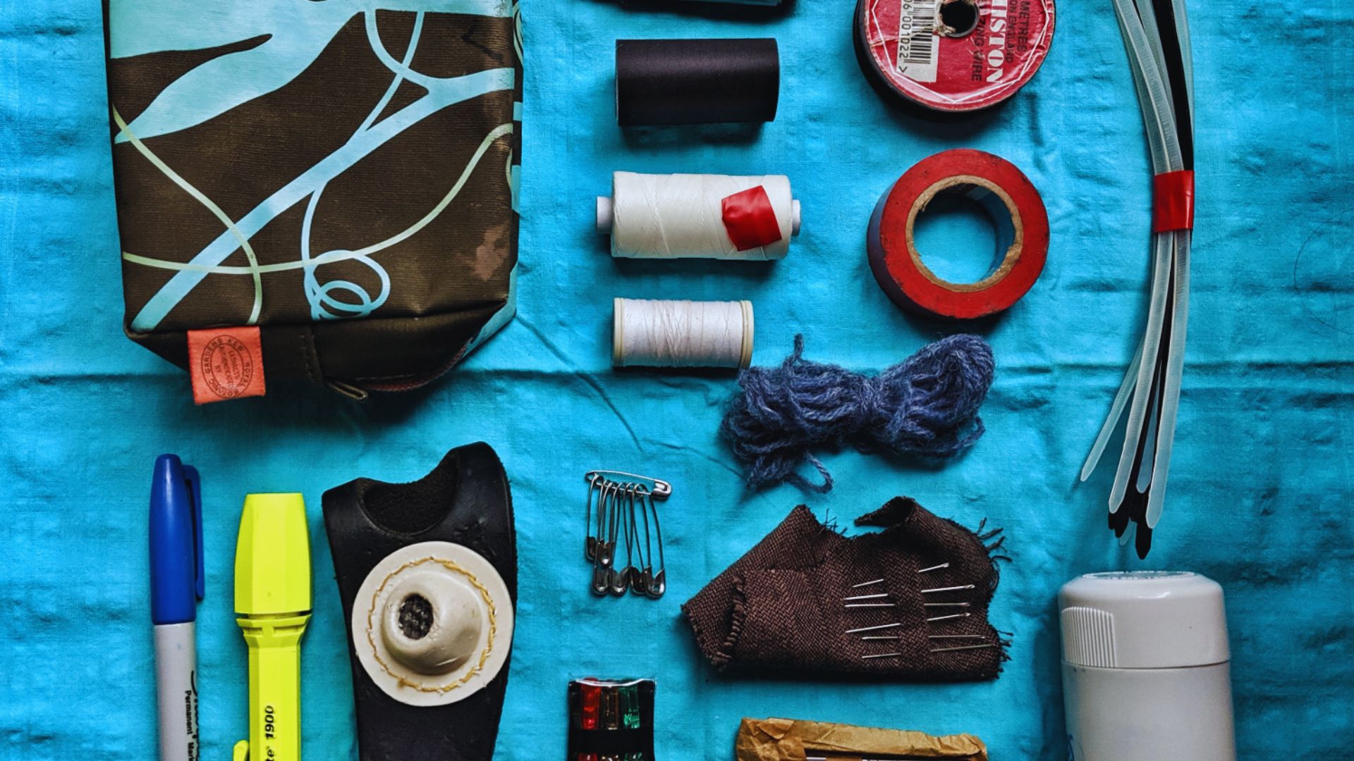 A sewing kit containing spools of thread, needles, scissors, and various fabric swatches arranged neatly.