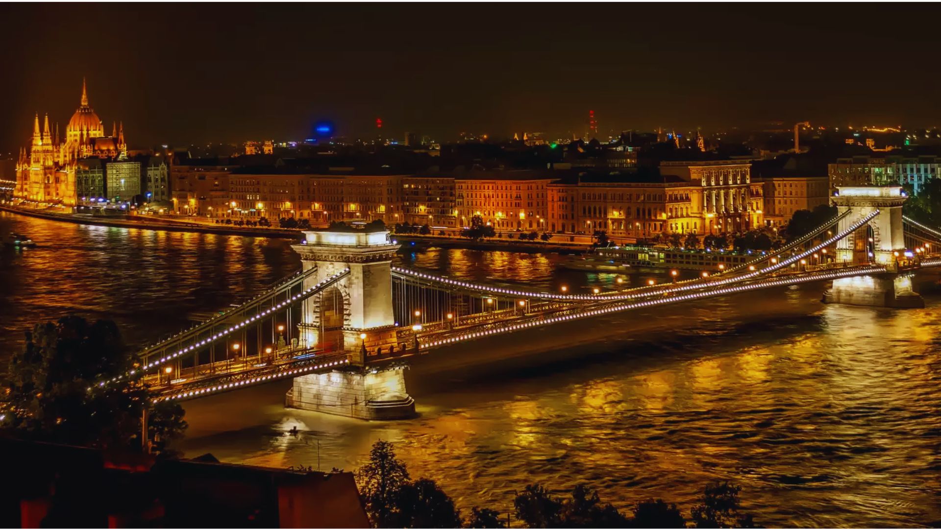 The Chain Bridge in Budapest illuminated at night, showcasing its architectural beauty against a dark sky.