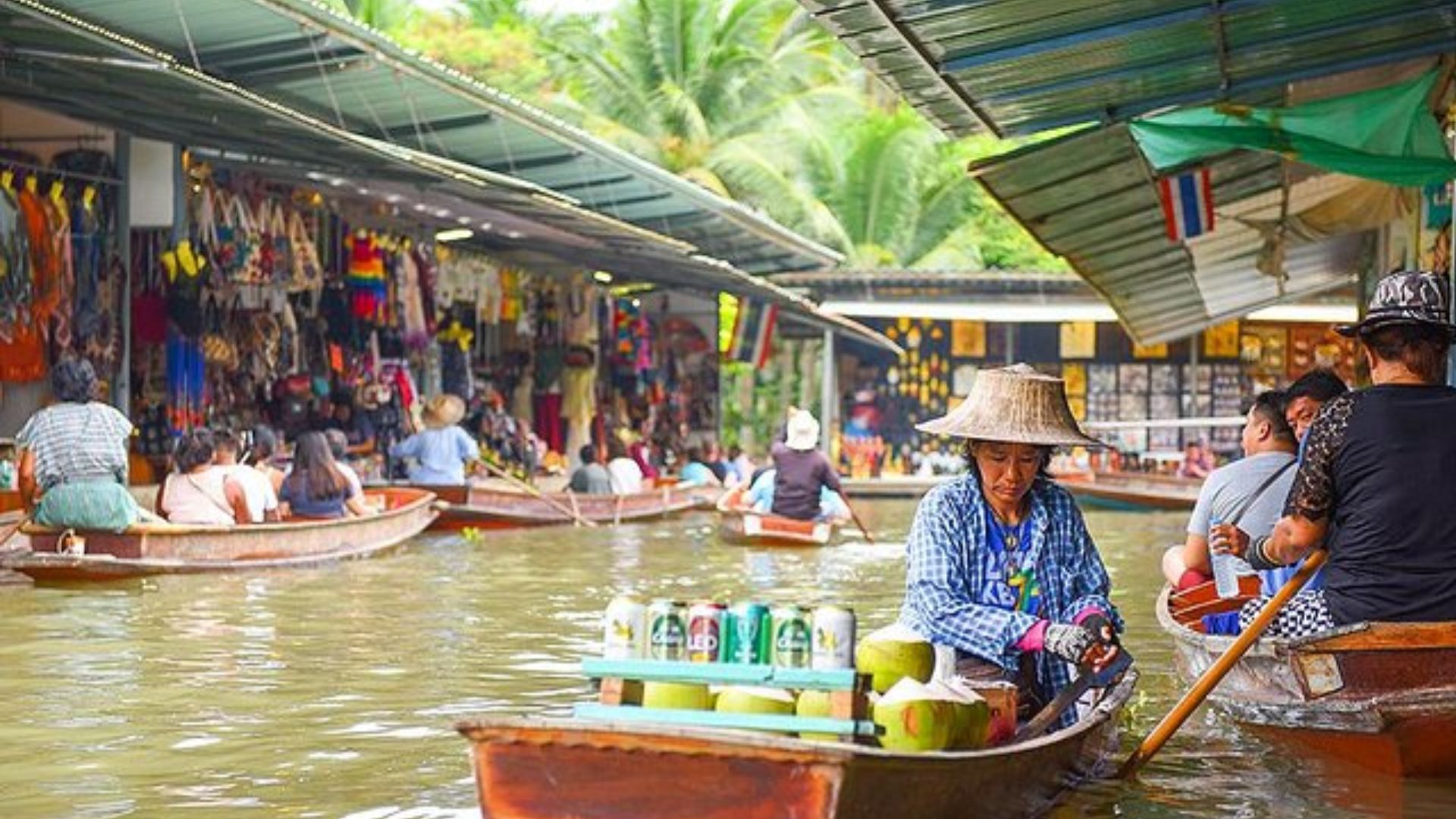 People in boats navigate a river lined with shops and bustling with pedestrians enjoying the vibrant atmosphere.